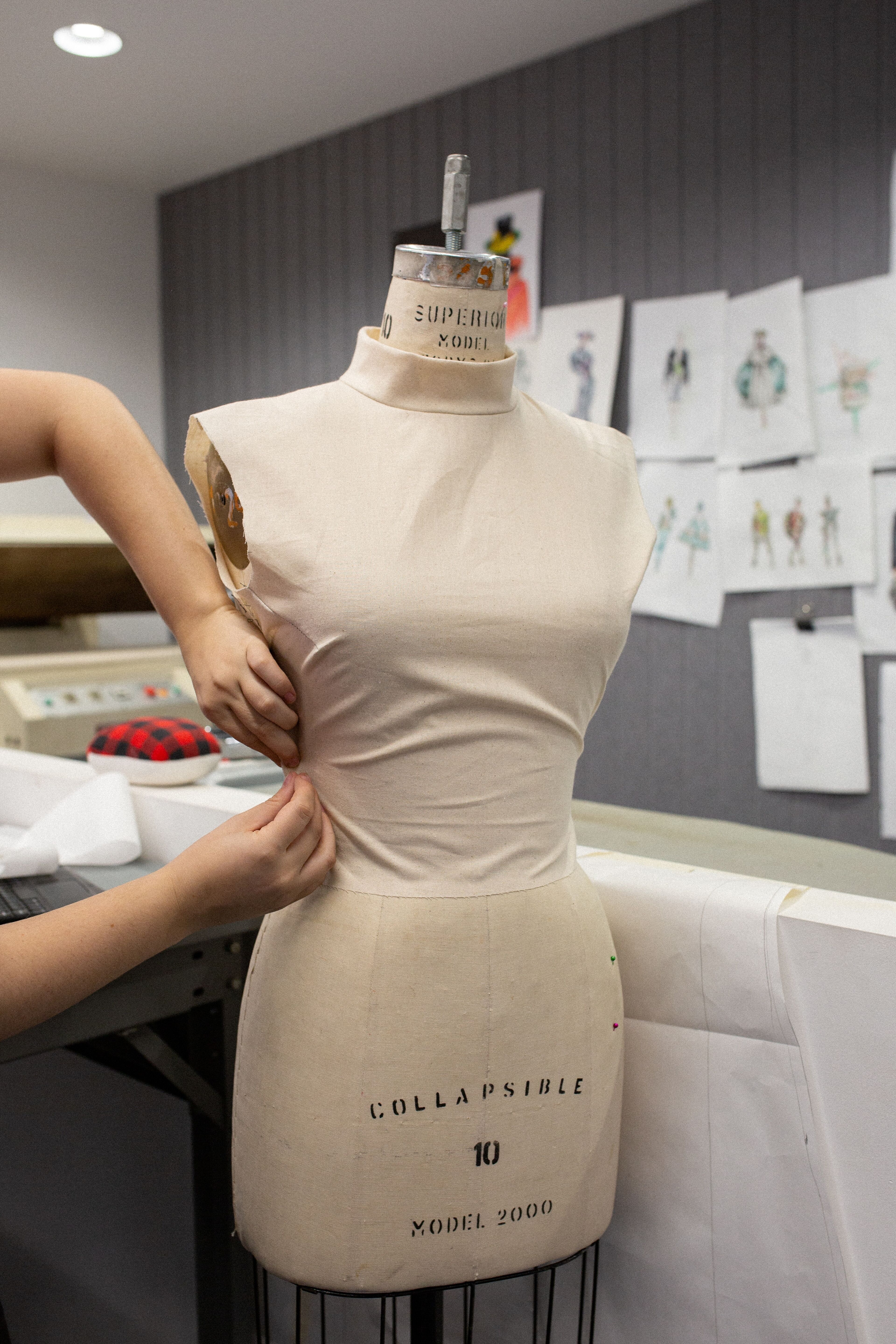 A designer drapes fabric on a dress form to sculpt the silhouette of a garment.