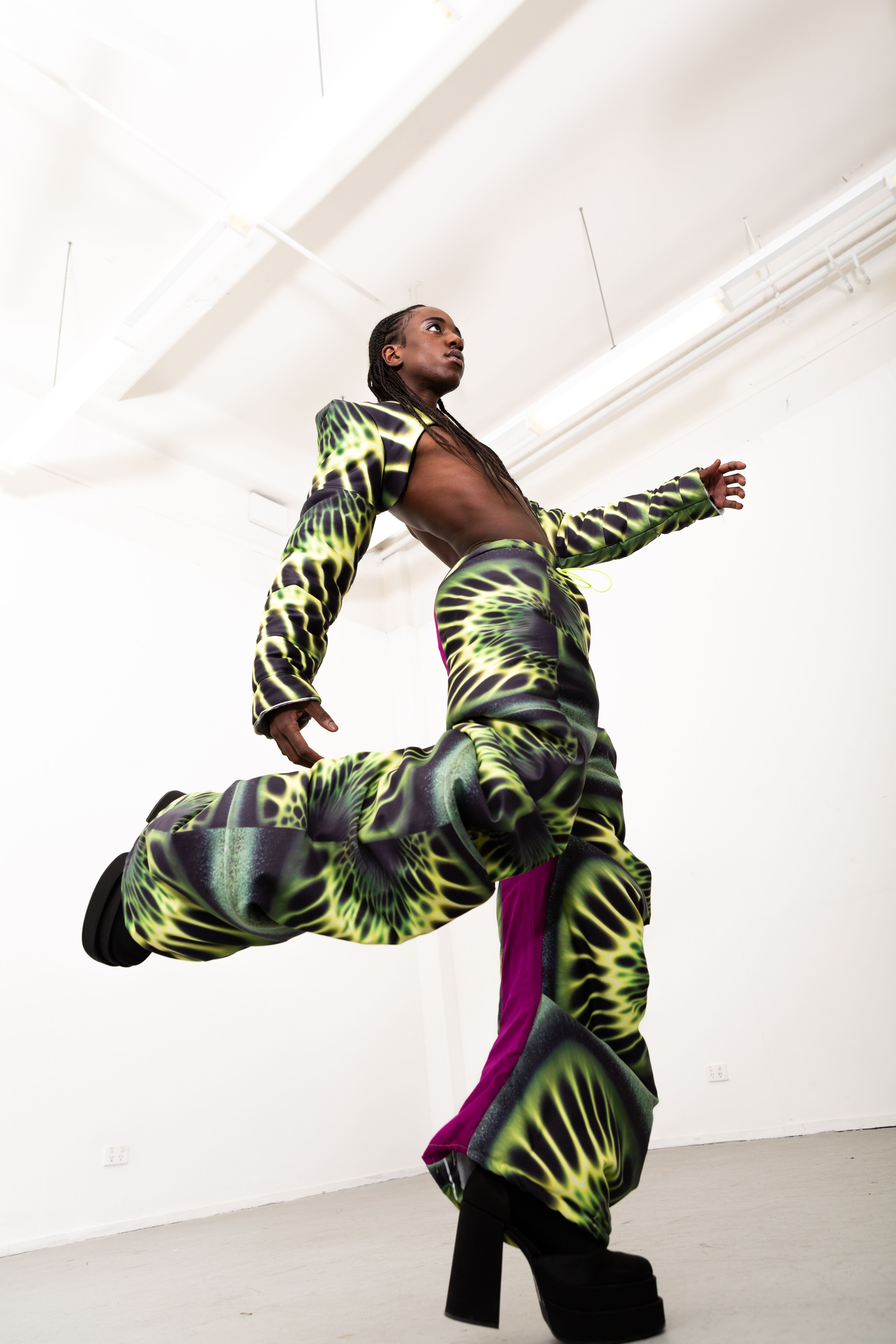 A model is captured a mid-movement pose, showcasing a bold, neon-patterned outfit.