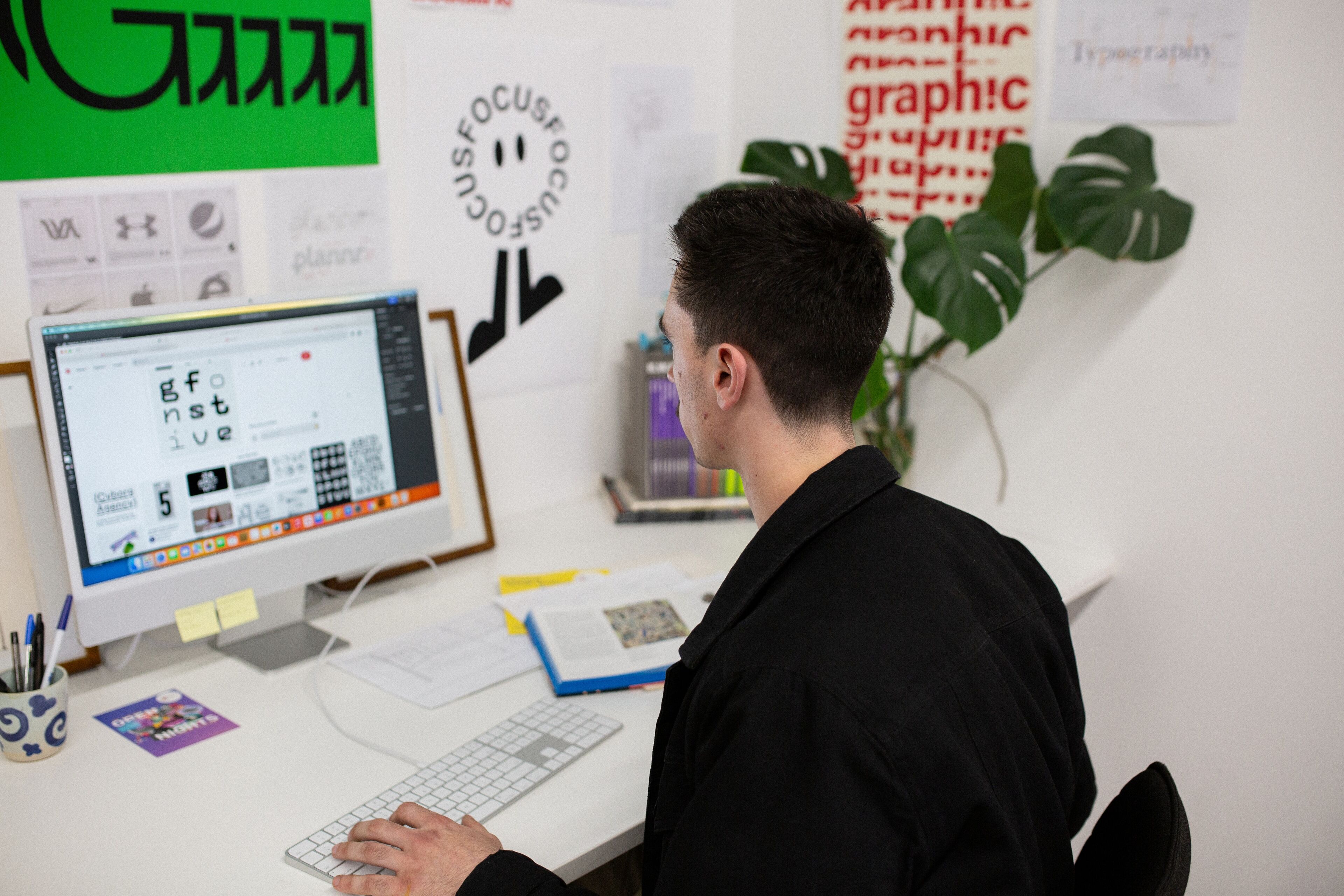 A graphic designer intently works on a typography project in a creative office space.