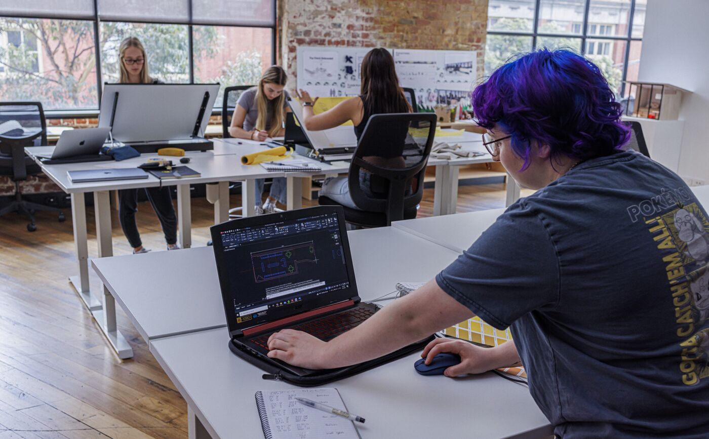 A diverse team of architects collaborate on a project, blending traditional drafting with modern CAD technology.