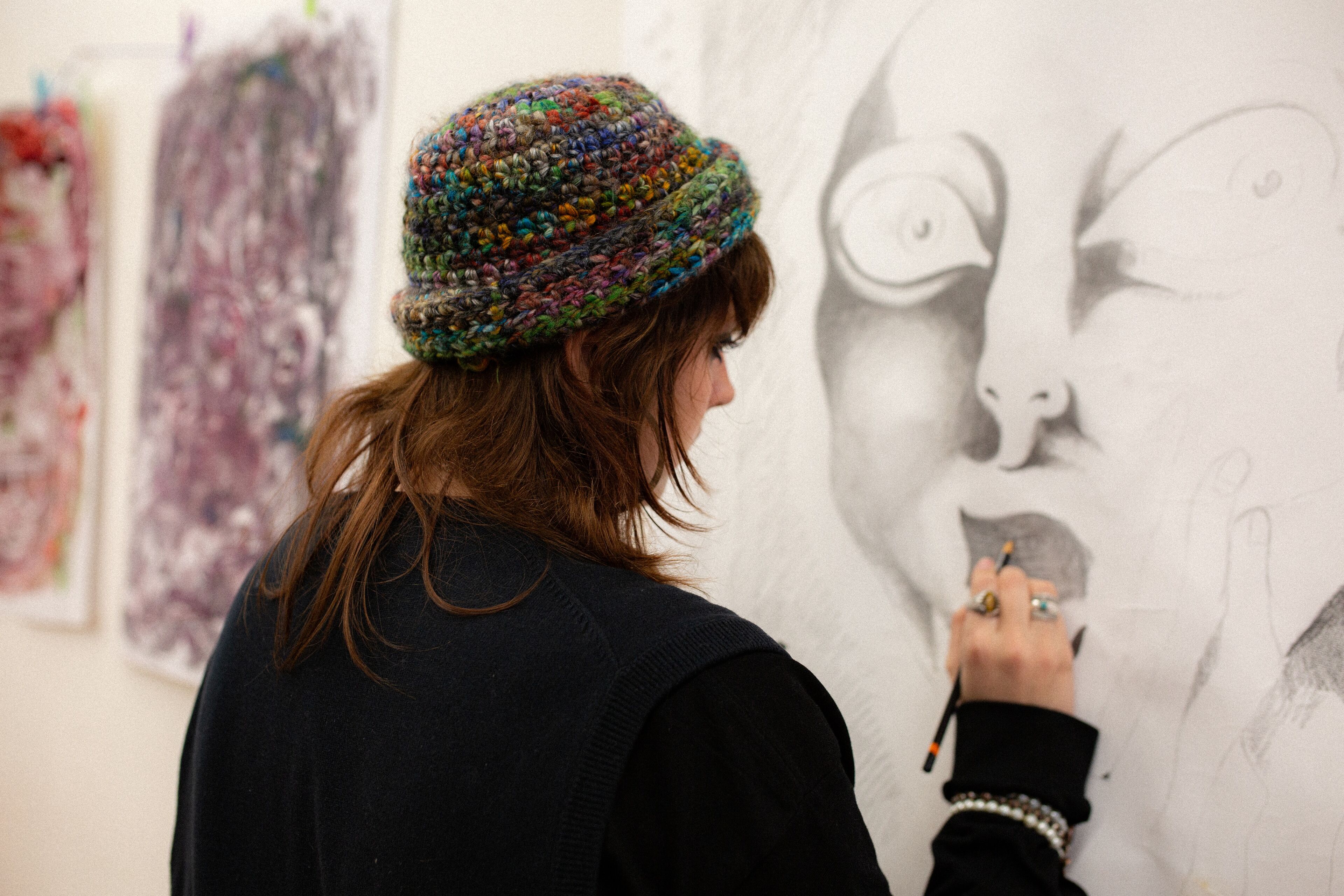 An artist meticulously sketches a portrait, engrossed in the act of bringing her visions to life.