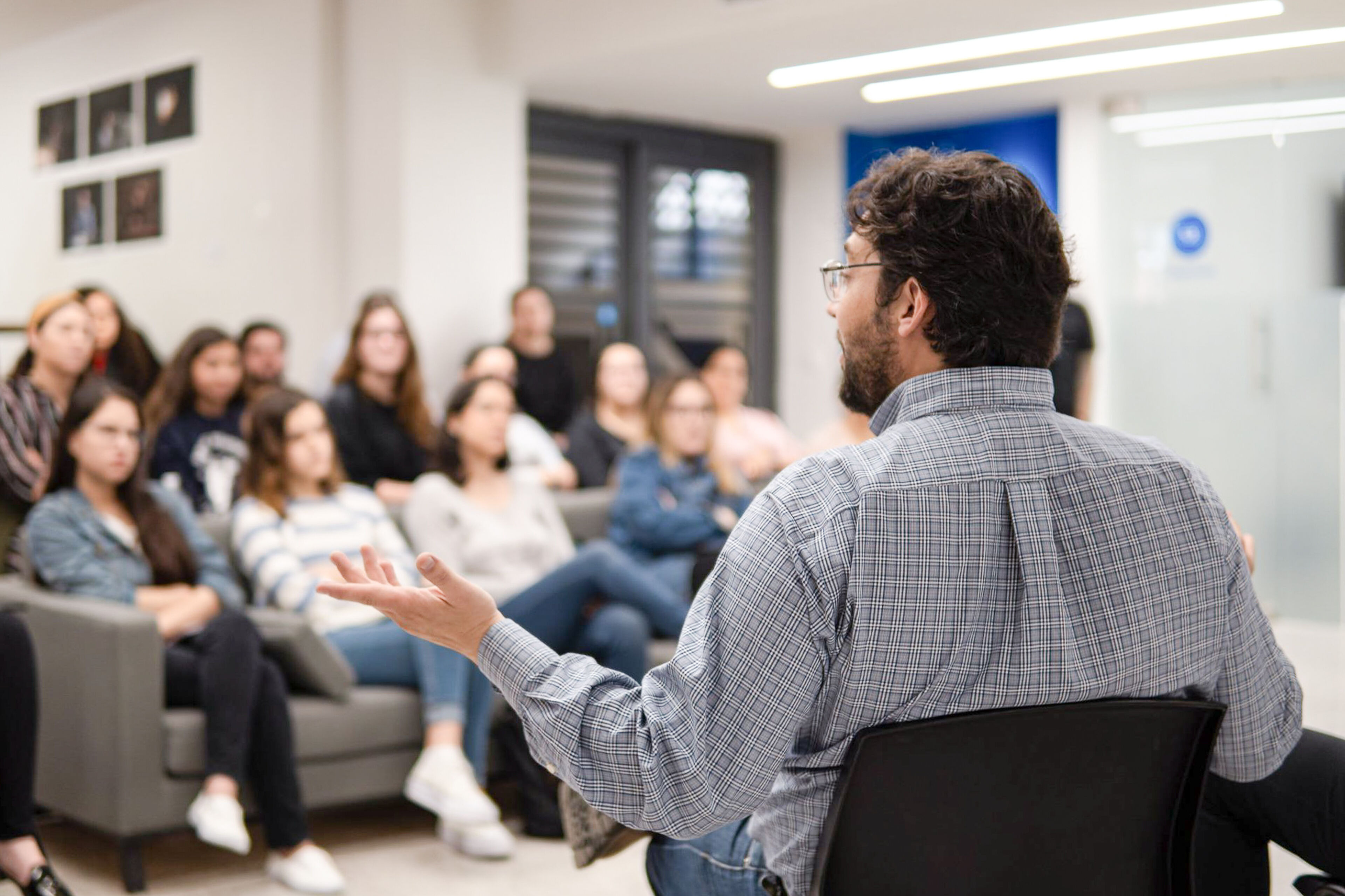 A speaker engages with an audience of attentive students in an educational setting.