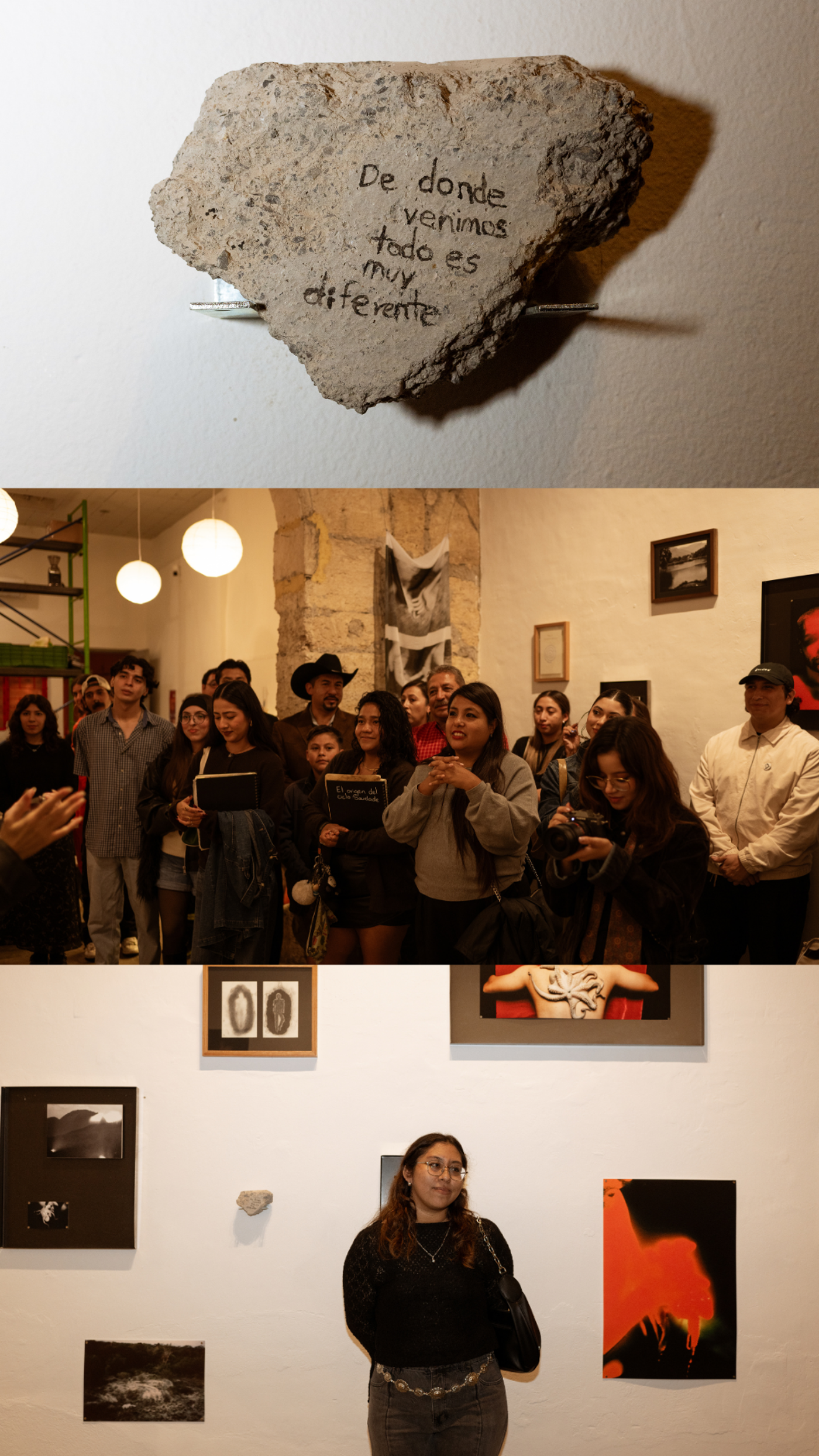 The image shows an art exhibition with a stone with text on it, and people looking at the art pieces. The atmosphere seems to be lively and engaging.