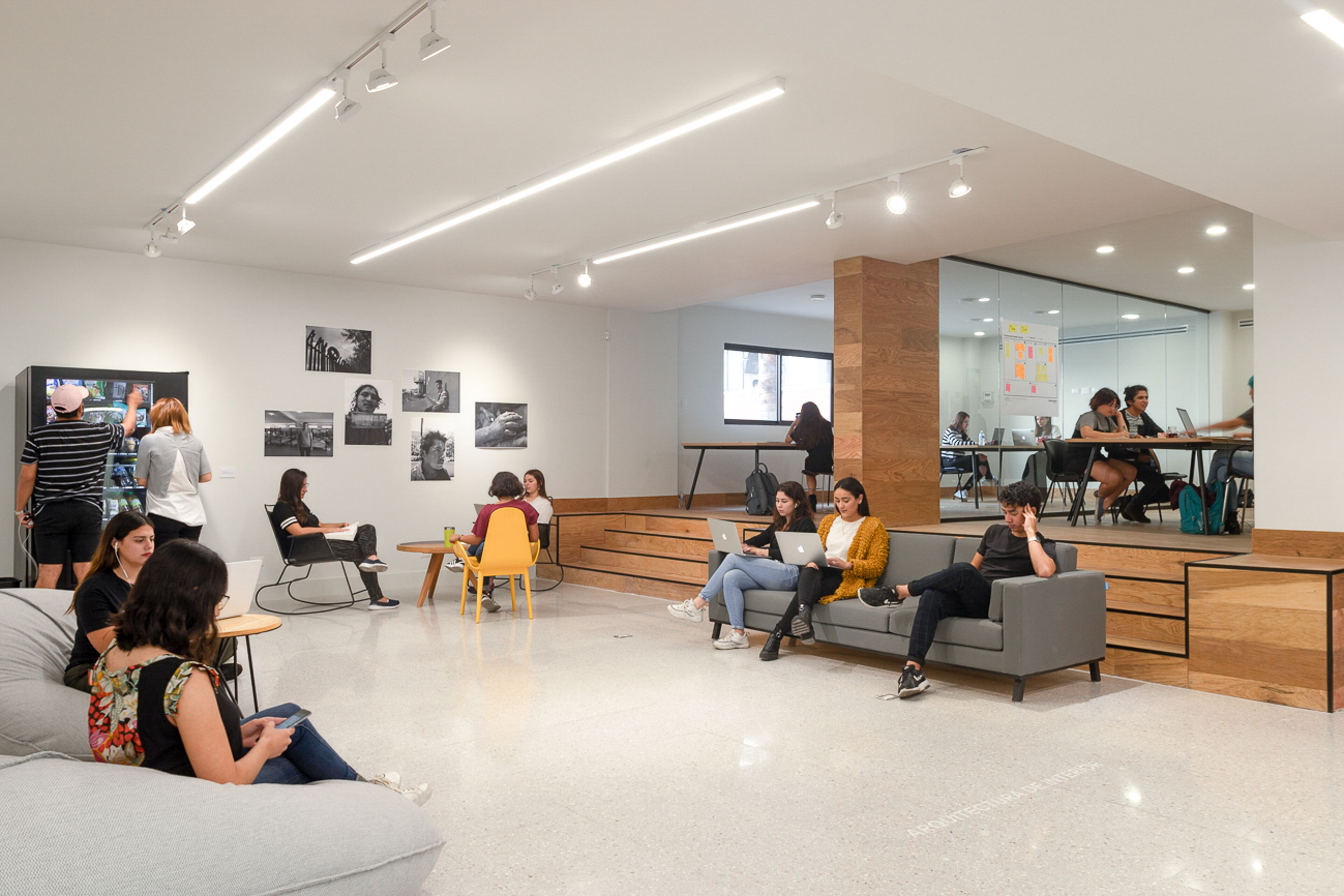 Students and professionals engage in work and discussion in a bright, modern communal space.