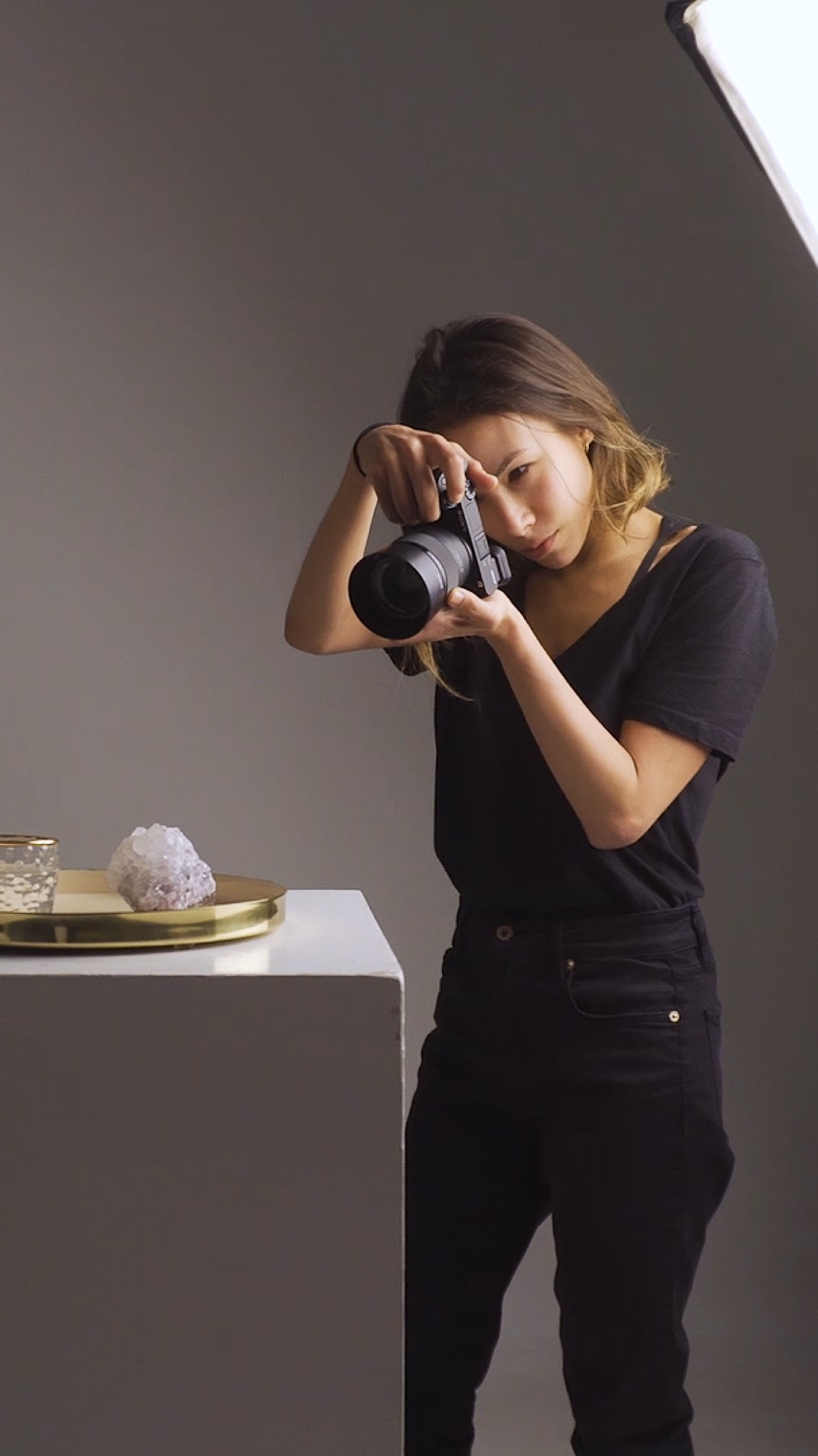 A focused photographer captures objects in a studio setup with professional lighting.