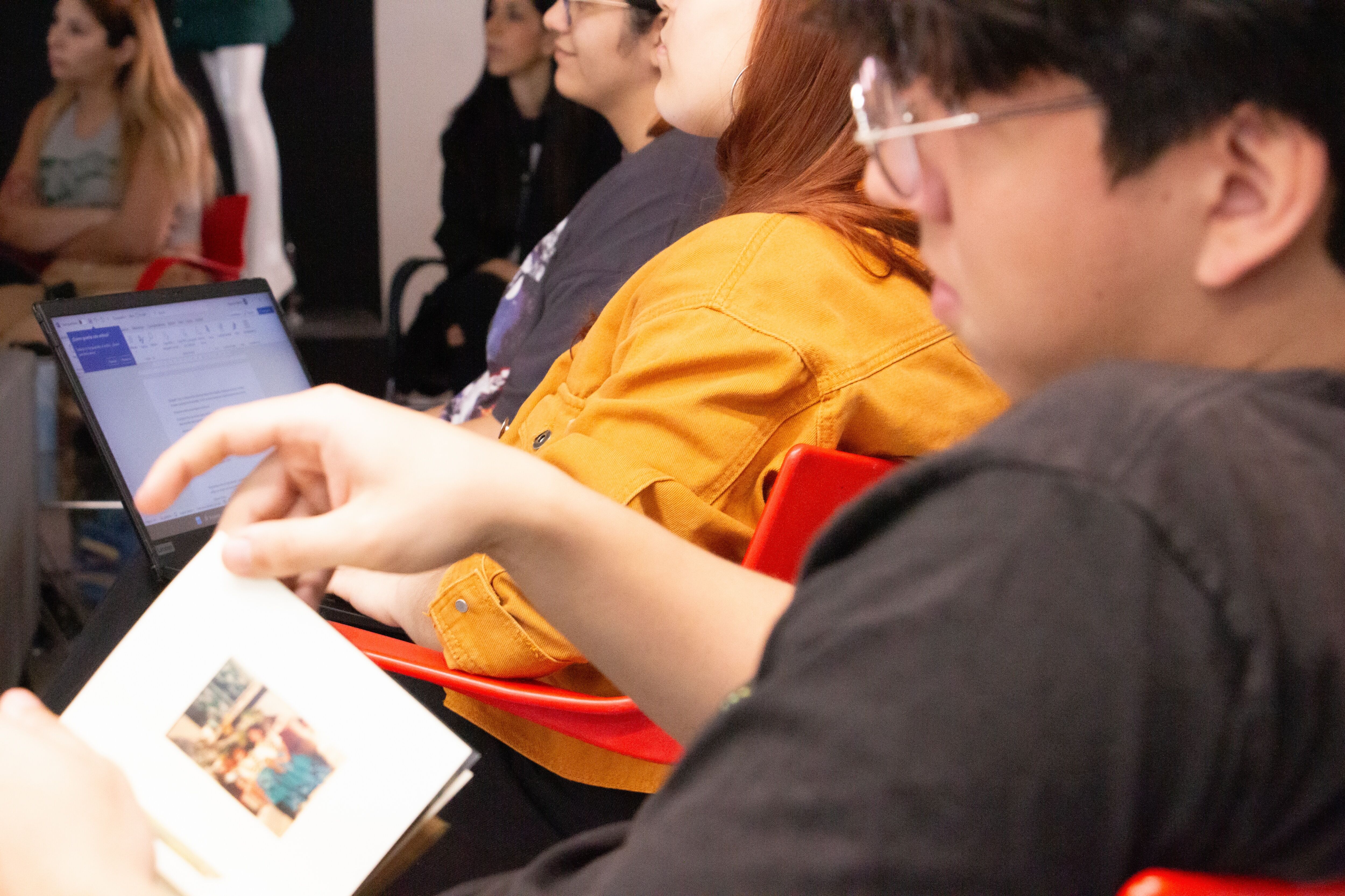 Estudiantes en un entorno de aula utilizando herramientas digitales y materiales impresos, destacando el aprendizaje activo y la participación.