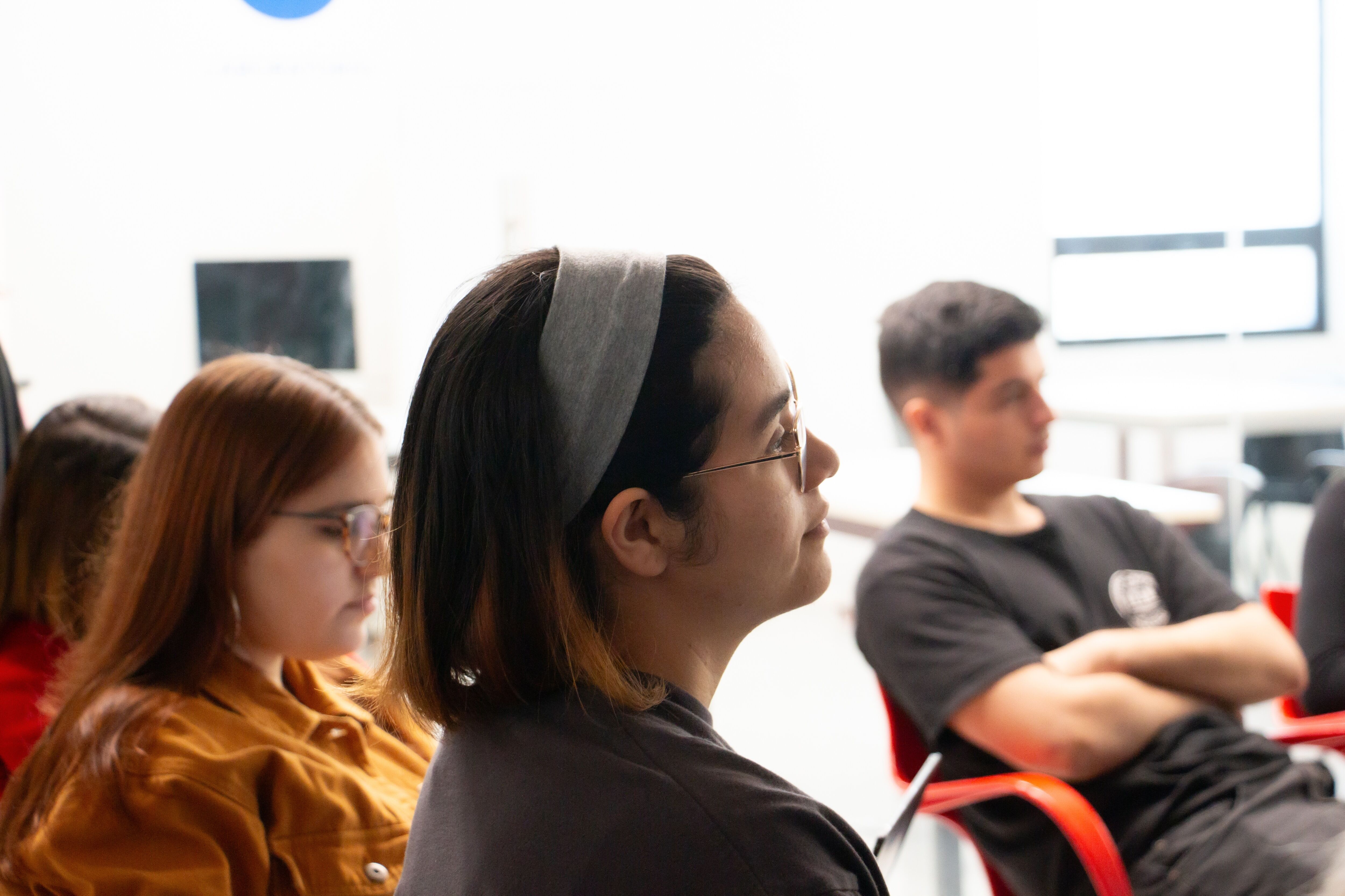 Un grupo de estudiantes escuchando atentamente en una conferencia, reflejando un entorno de aprendizaje diverso y comprometido.