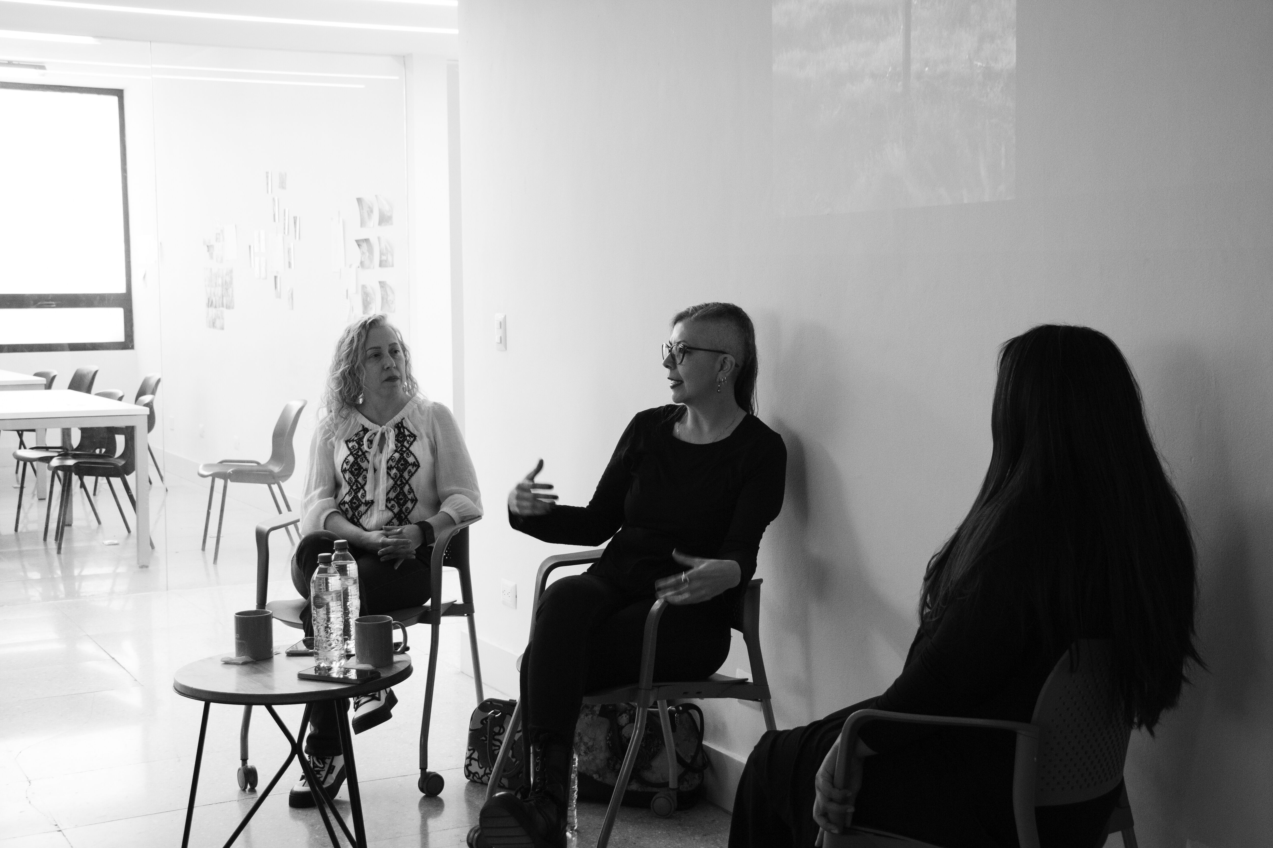 Tres participantes discuten activamente sobre métodos educativos en un ambiente de clase, enriqueciendo la experiencia de aprendizaje mediante un diálogo abierto.