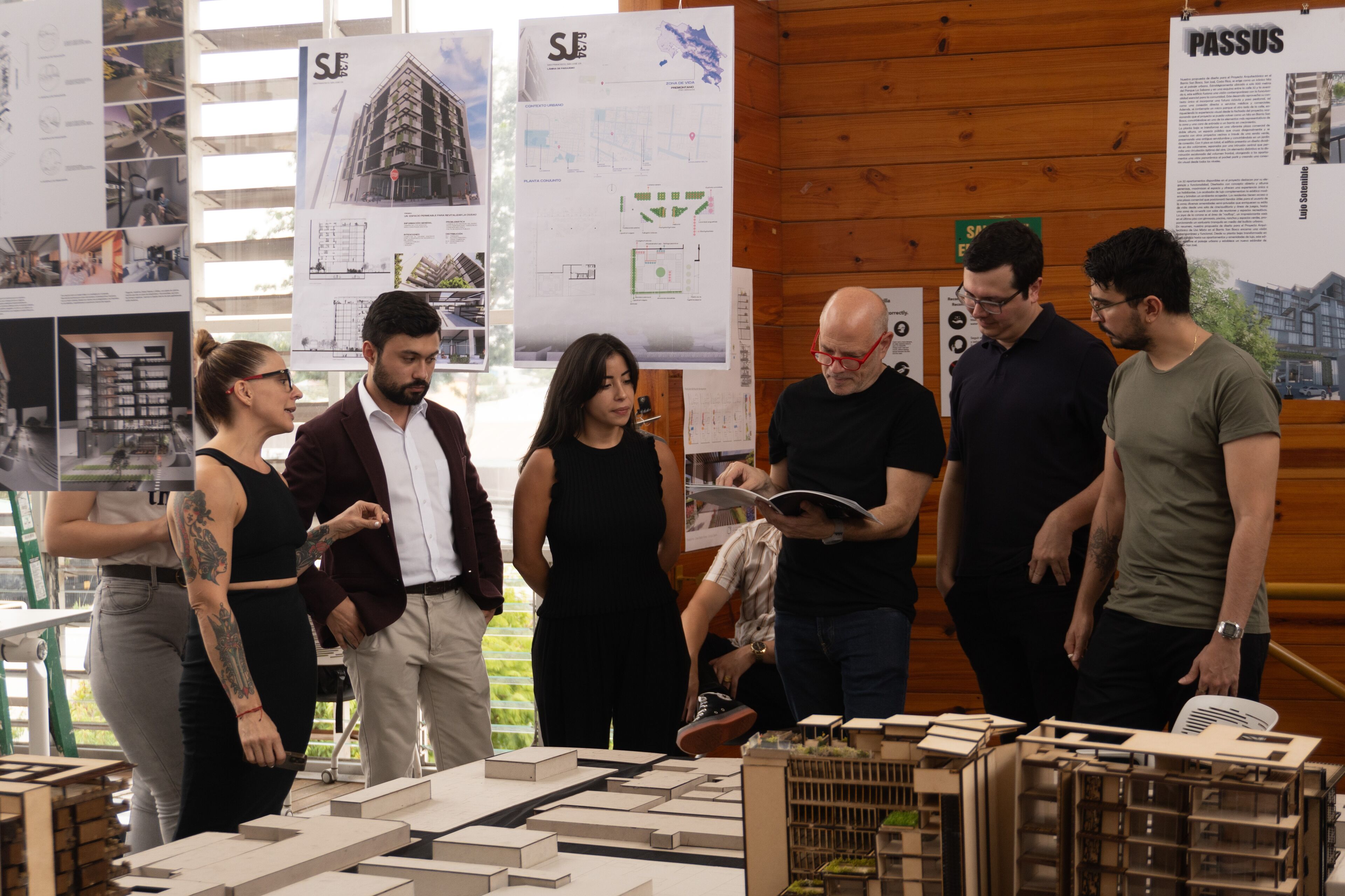 Group of focused architects discussing project details around scale models and design blueprints in a bright workspace.