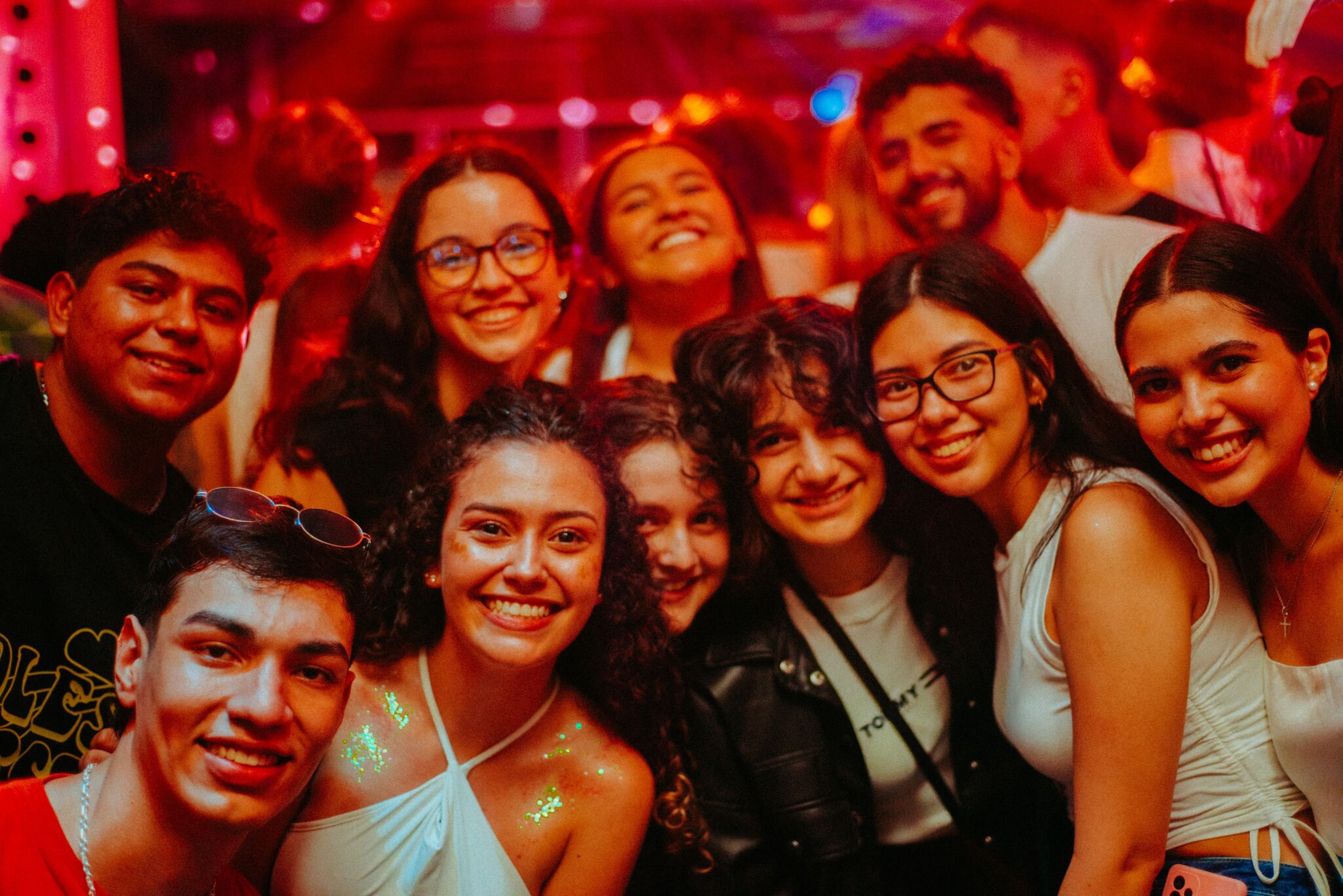 A cheerful group of young adults smiling at a festive event with warm ambient lighting.