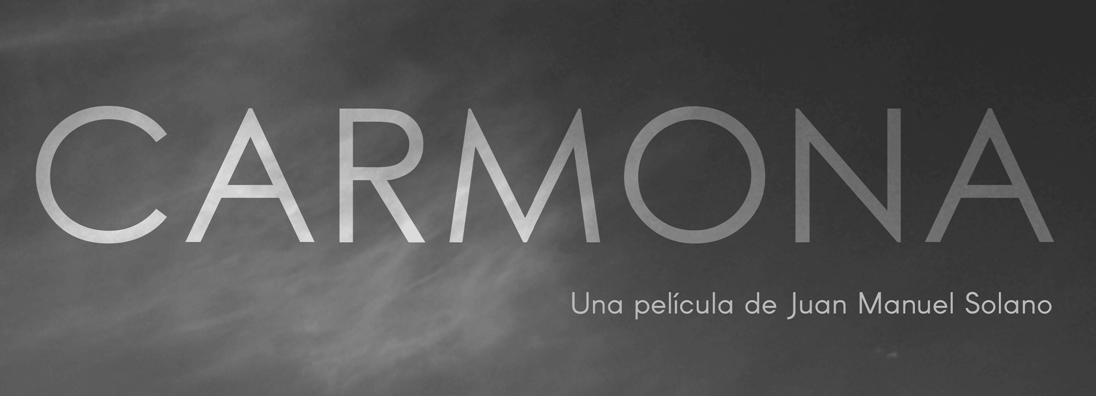 Cartel de título para una película, presentando la palabra "CARMONA" en letras blancas grandes contra un fondo en escala de grises nublado, con un subtítulo en español.