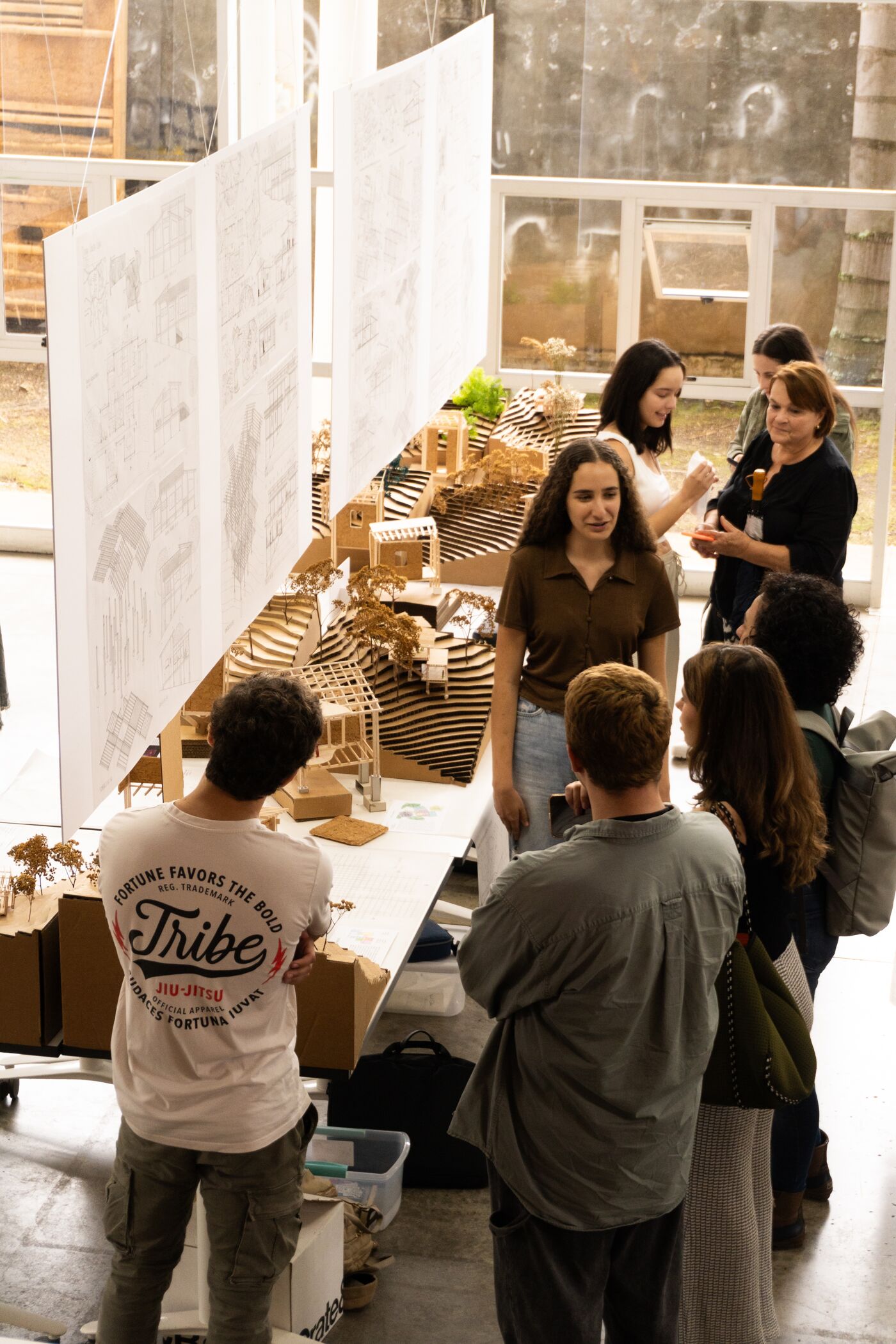 Group of individuals engaging in a discussion around architectural models and blueprints in a workshop setting.