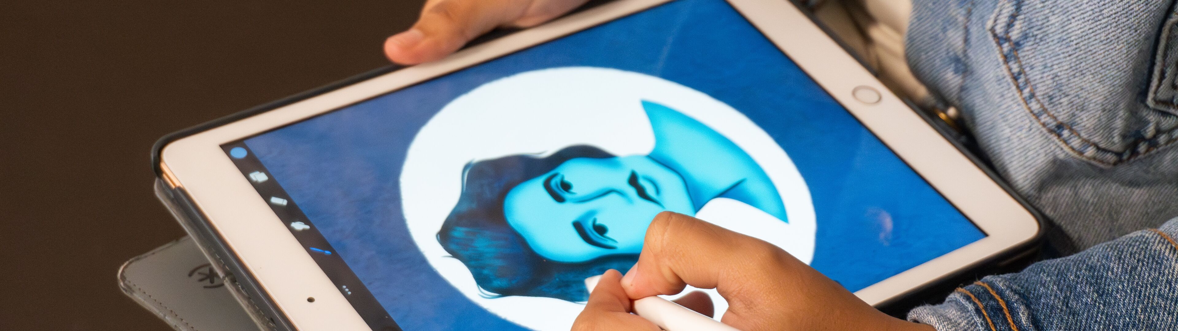 Mano de artista usando un lápiz óptico para dibujar un retrato en tonos azules en una tableta digital.