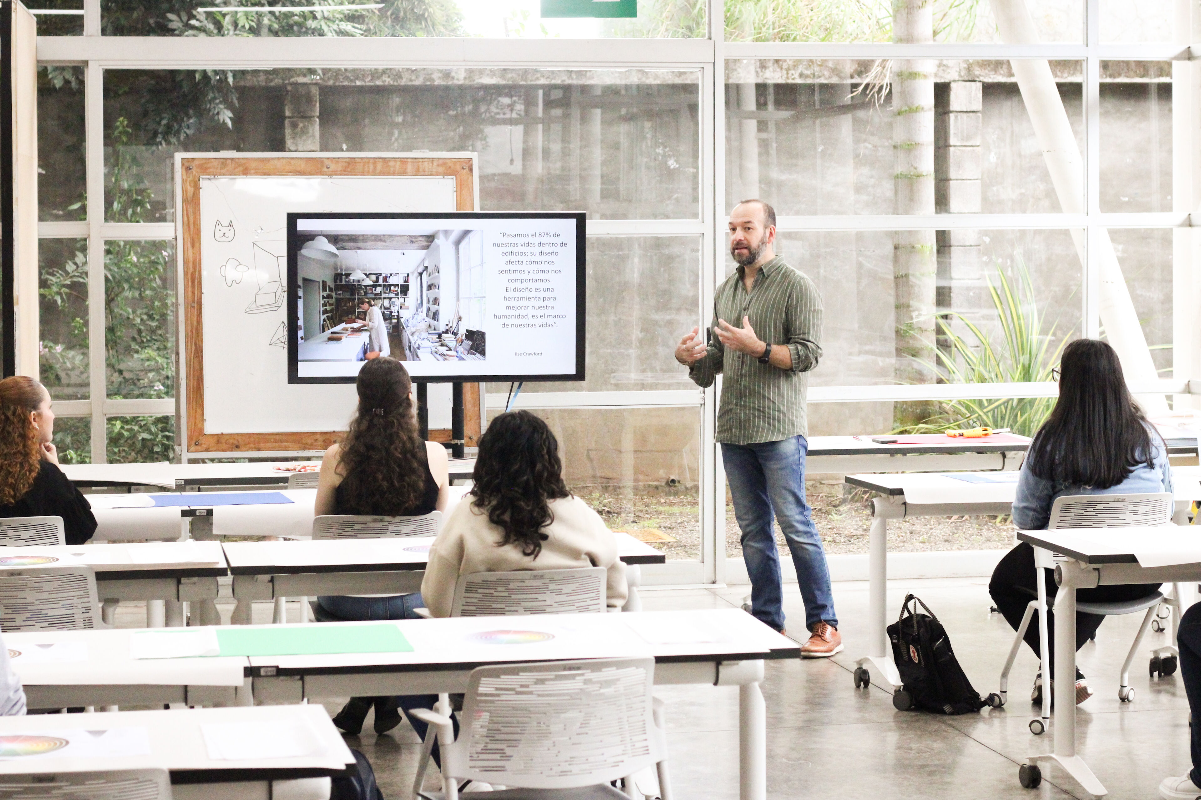 A man giving a presentation to a small group in a bright, modern workspace.