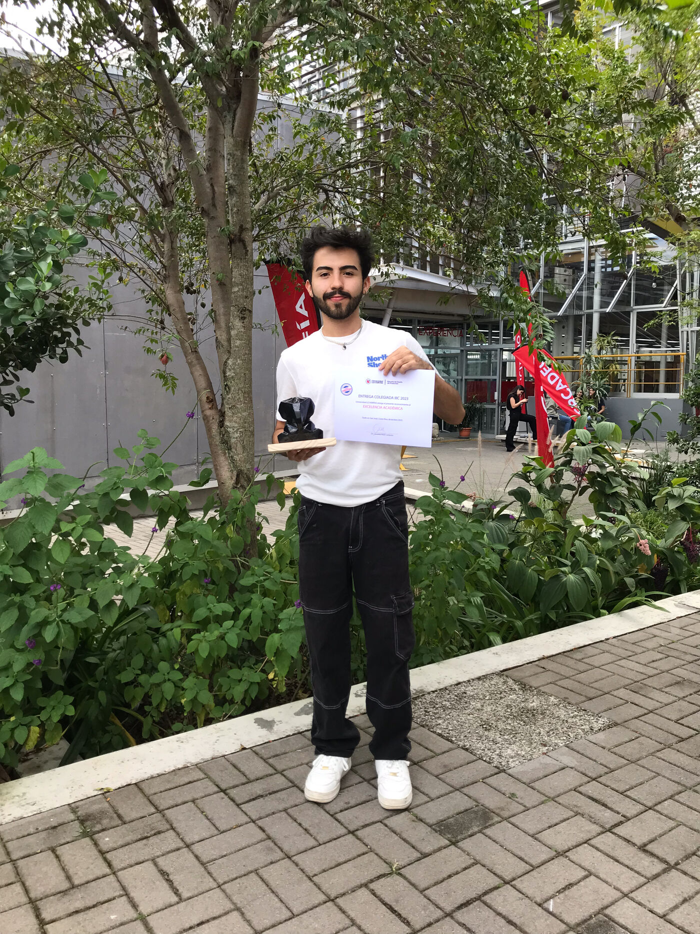Hombre con certificado y trofeo al aire libre