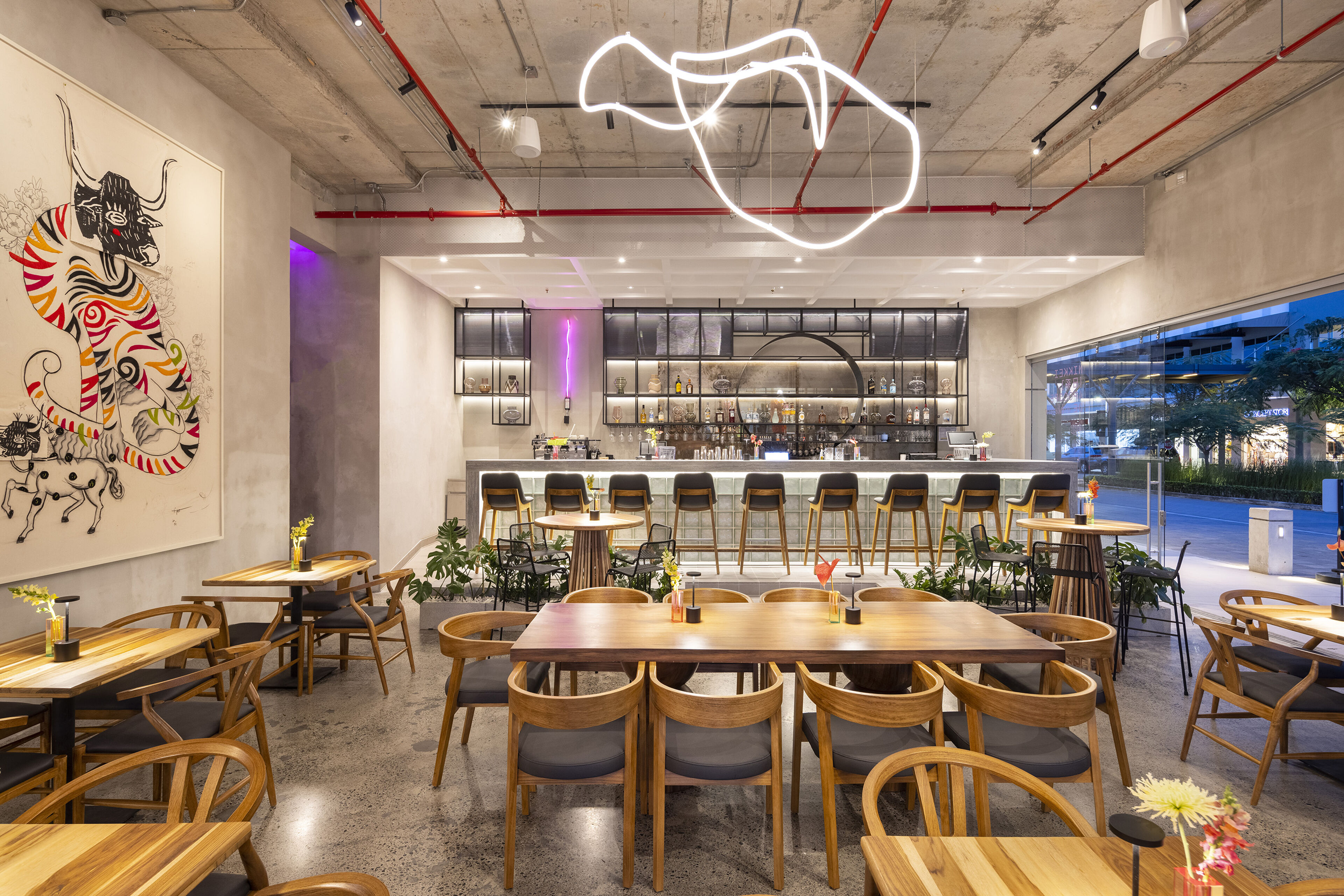 Un café moderno con decoración artística de paredes, iluminación ecléctica y una zona de bar con estilo.