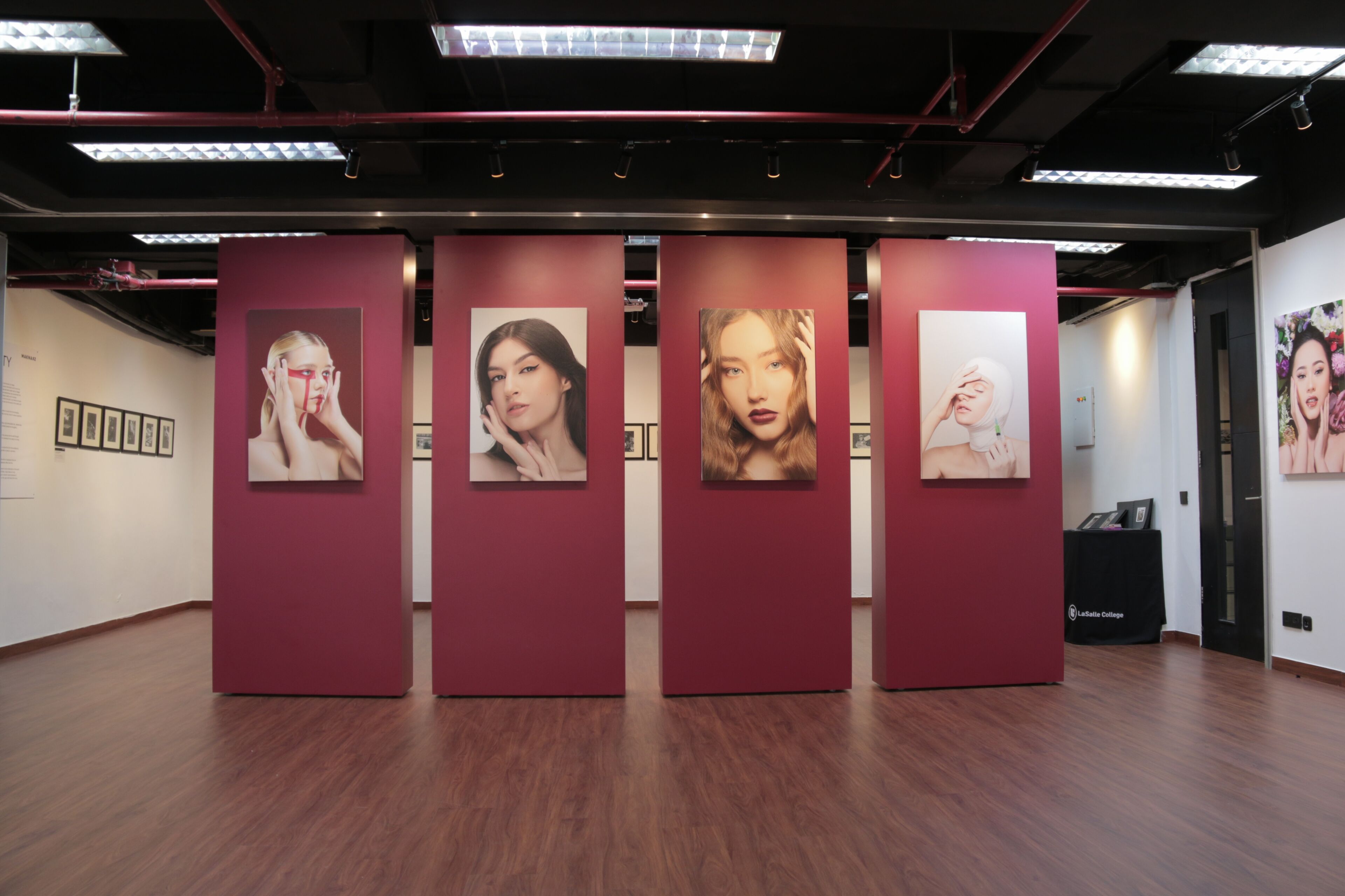 A modern art gallery displays large portraits of women against maroon panels, with a sophisticated ambience.
