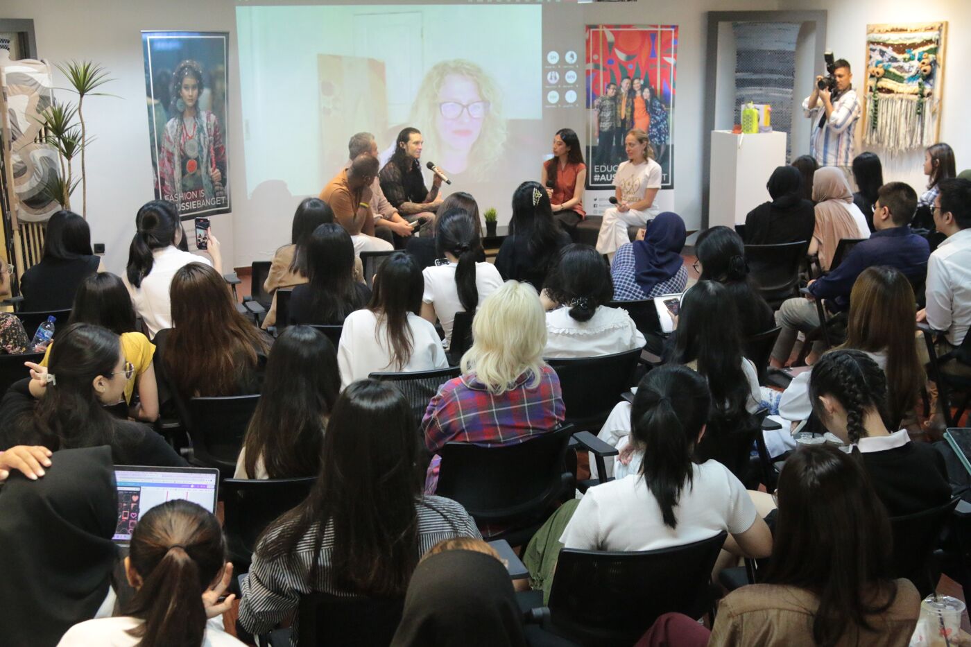 A room filled with attentive audience members seated facing a panel discussion at an educational seminar.