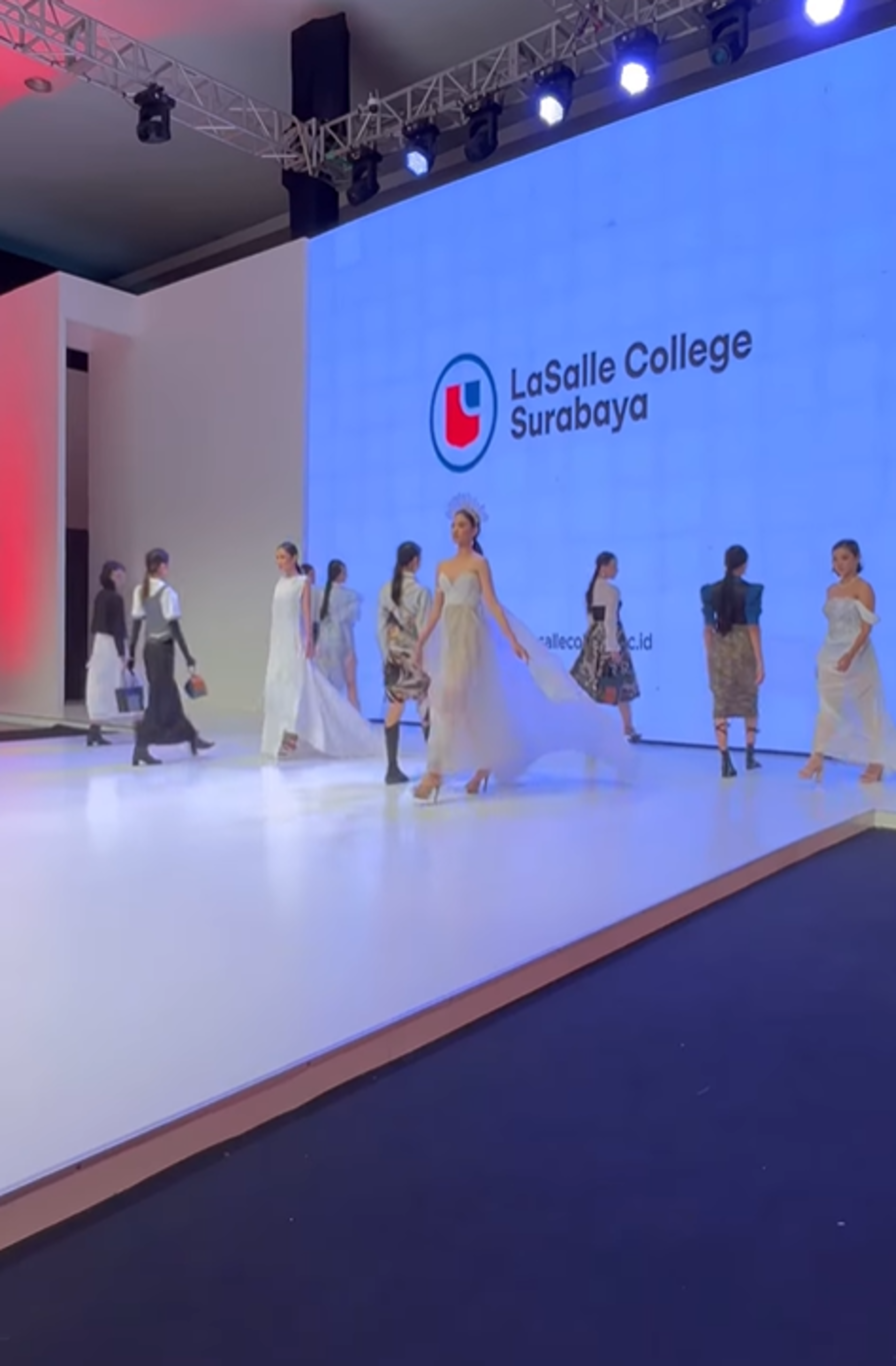 Models showcase elegant and innovative designs by LaSalle College Surabaya's fashion design students. The runway features flowing dresses and modern silhouettes, highlighting the students' creativity and skill in blending contemporary and classic elements.