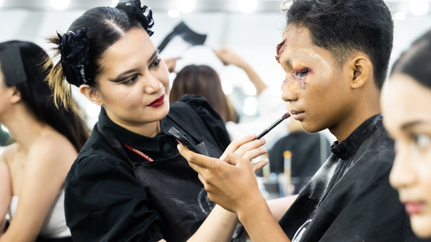A makeup artist applies special effects makeup to create a realistic injury on an individual's face.