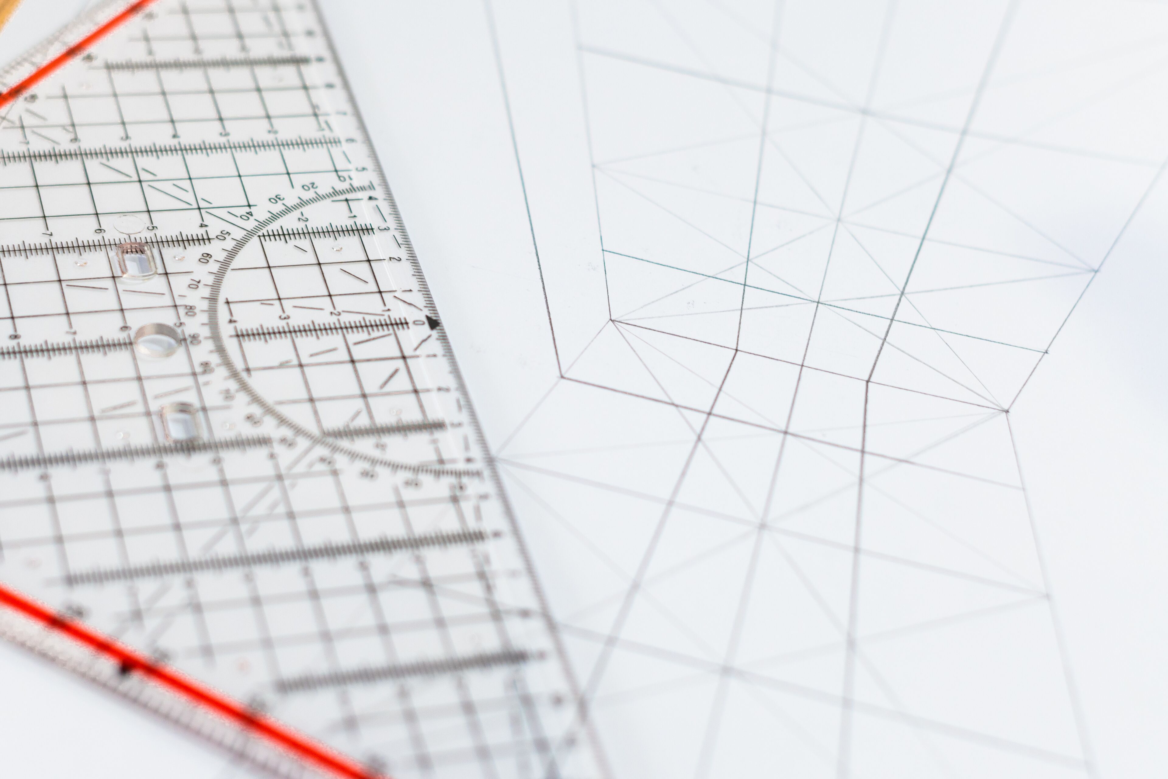 Transparent rulers with a protractor overlay geometrical shapes on paper.
