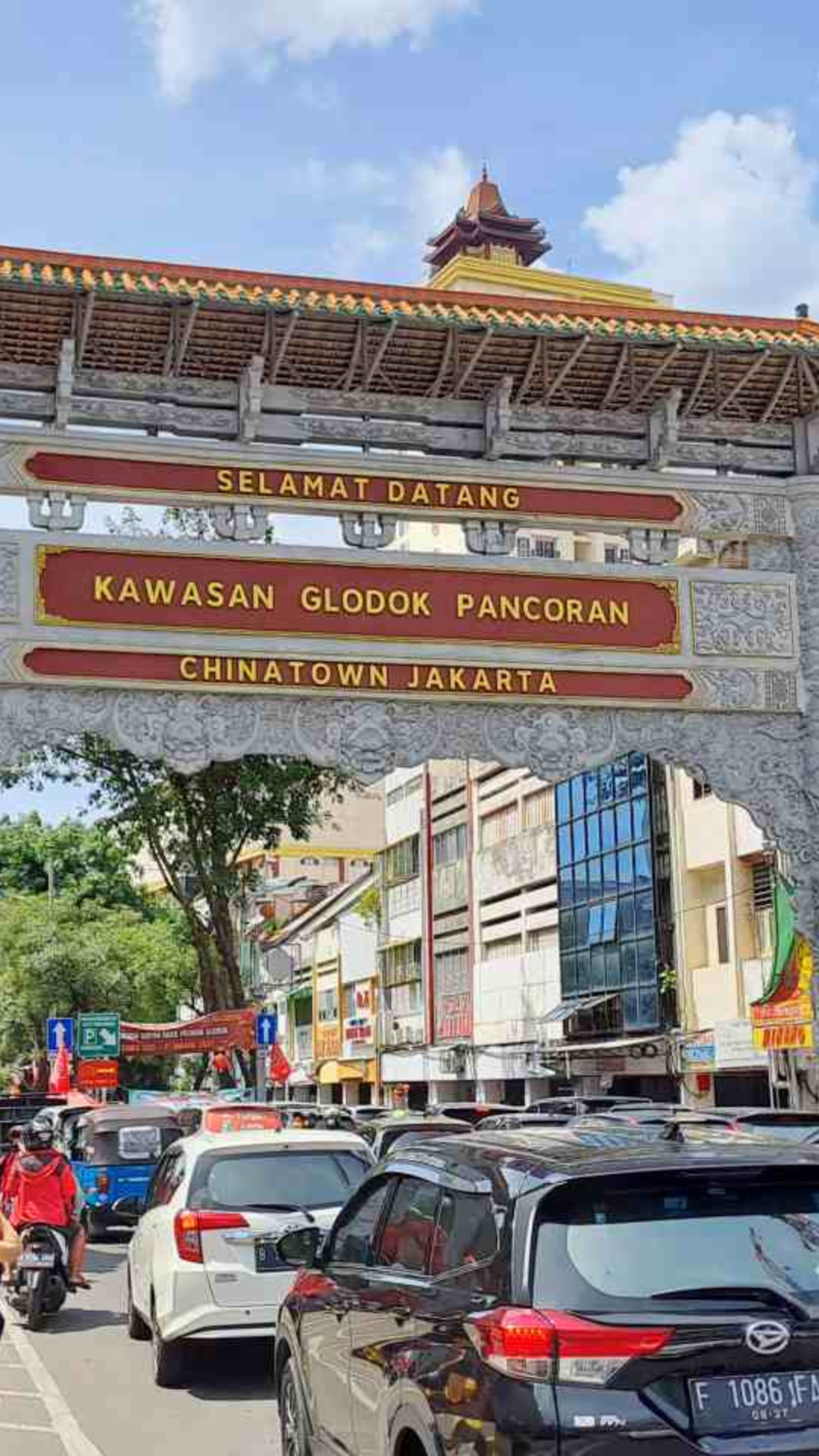 An ornate gateway welcomes visitors to Glodok, the vibrant Chinatown area of Jakarta, under a sunny sky.