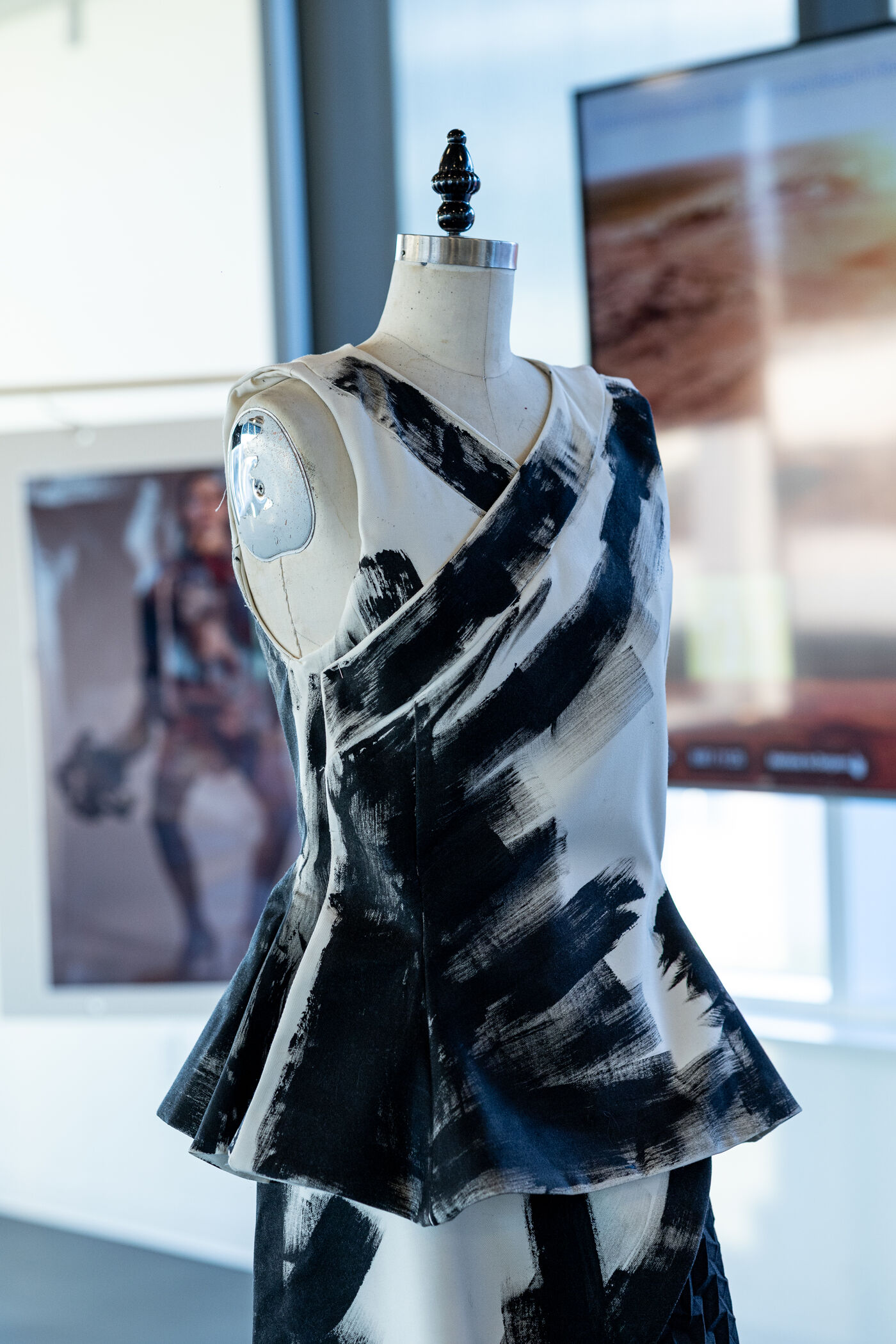 A white dress featuring a black abstract paint-splatter design, with a peplum silhouette reminiscent of a modern art piece.