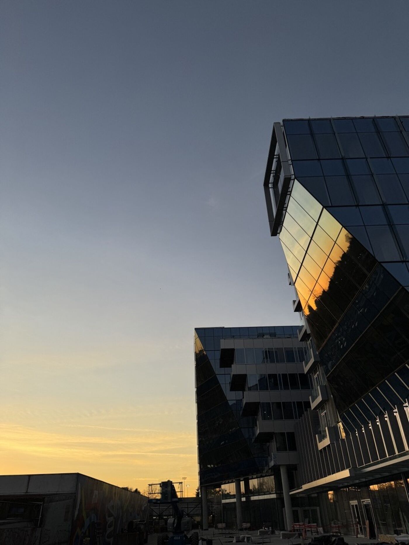 Modern glass buildings are silhouetted against a vibrant sunset.