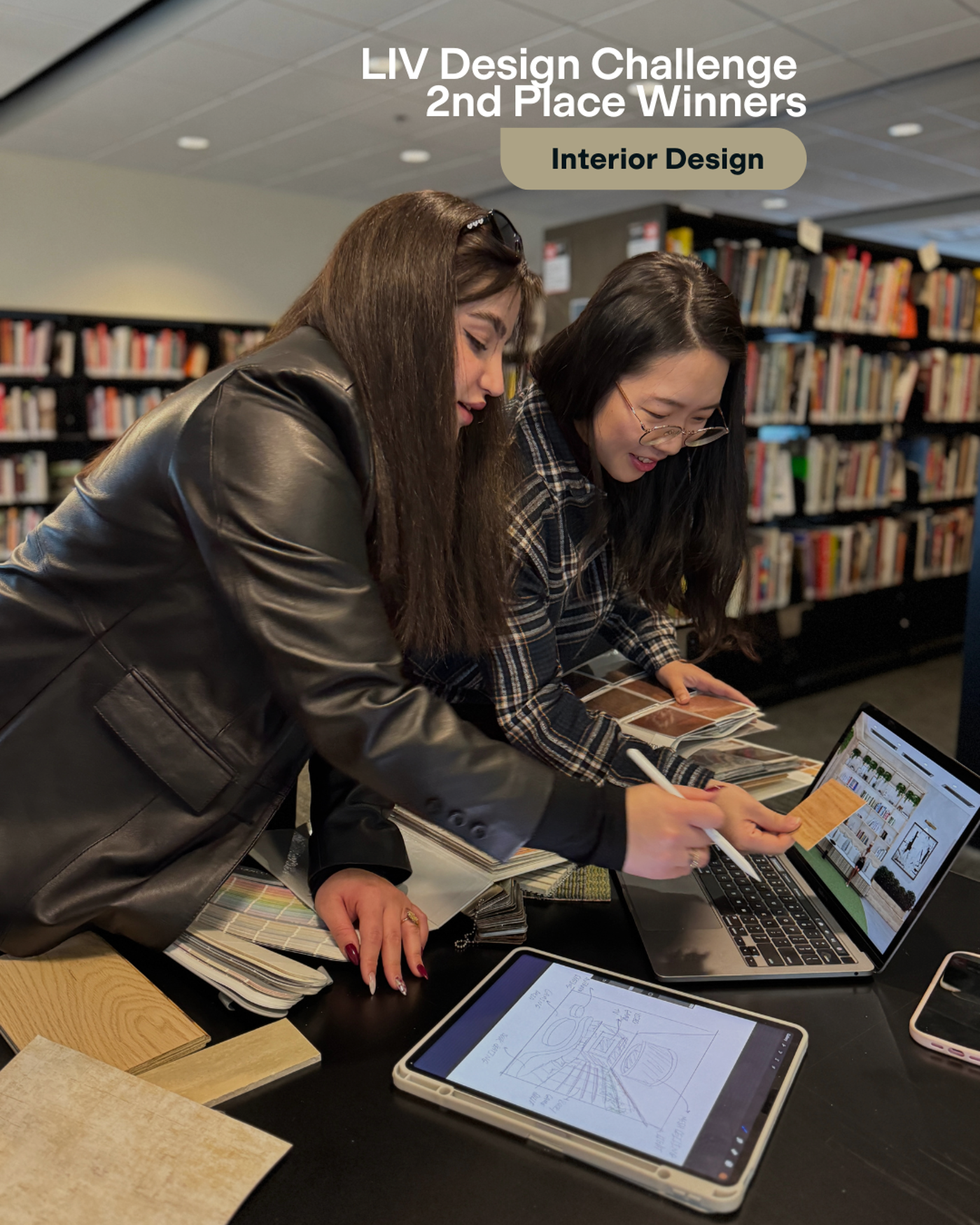 Two young women, winners of a LIV Design Challenge, collaborate on an interior design project using laptops and sample materials in a library setting.