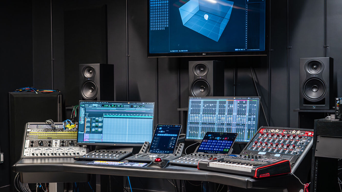 A professional sound recording studio setup with multiple monitors, audio interfaces, mixers, and speakers, indicating a space for music production and audio engineering.