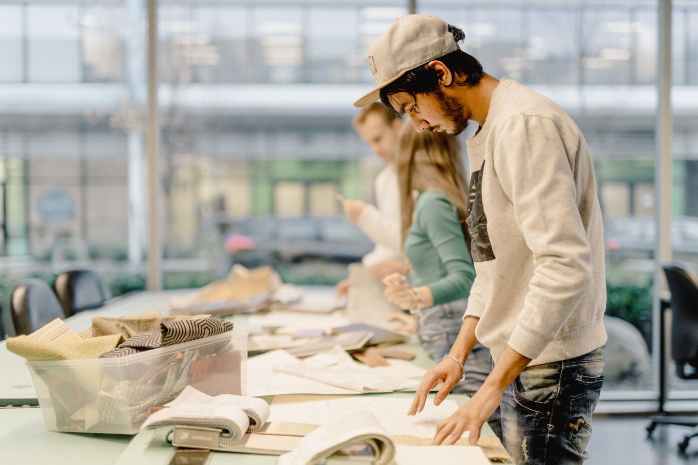 Students engaged in selecting materials for their fashion design projects in a well-lit studio.