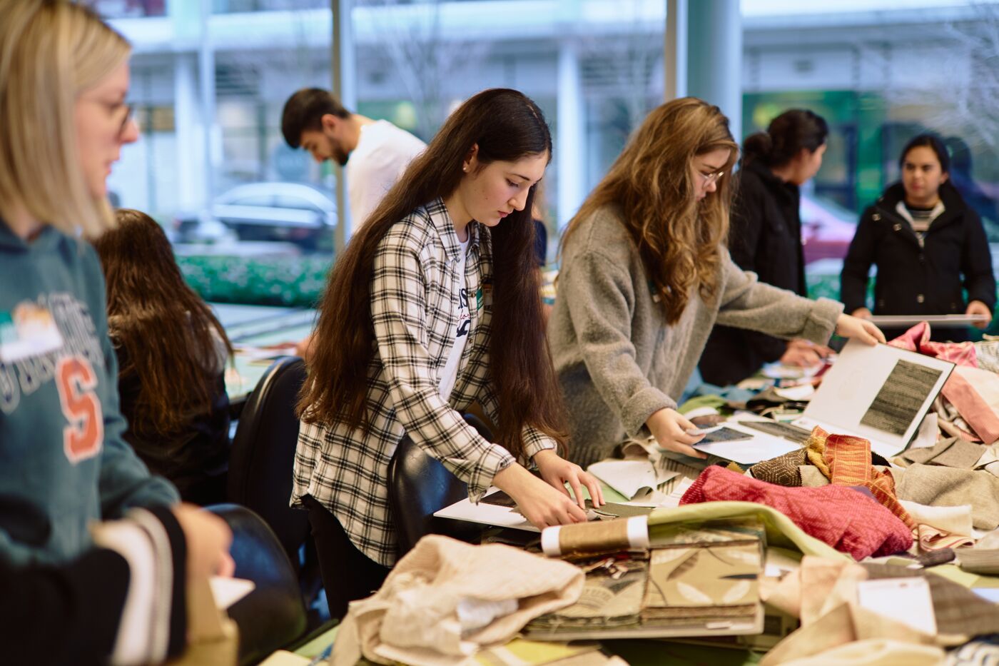 Concentrated students work on textile projects in a bustling workshop.