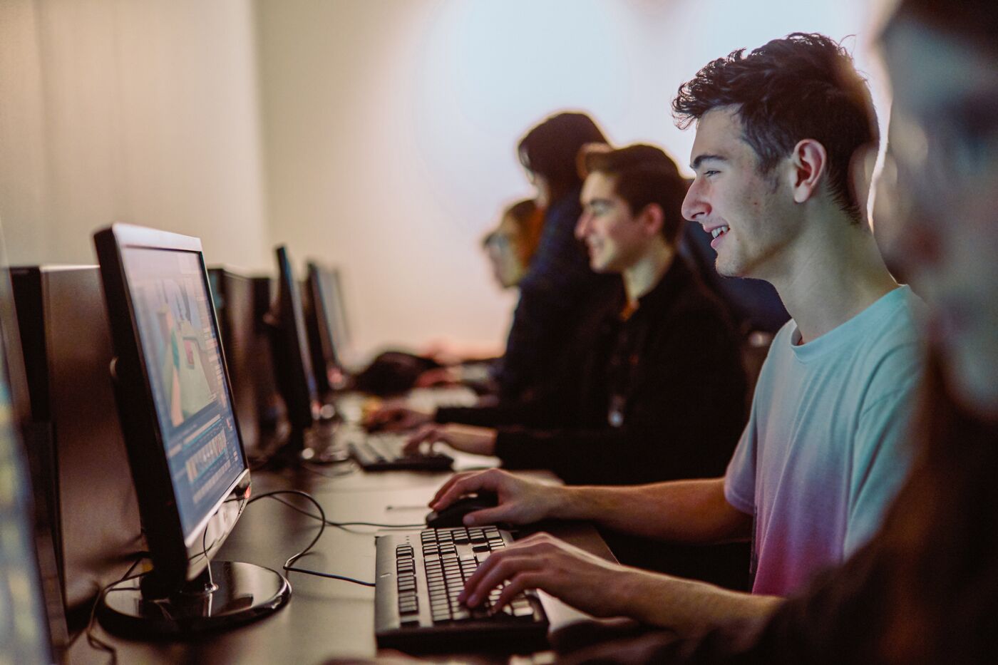 Group of focused individuals working on computers in a row.