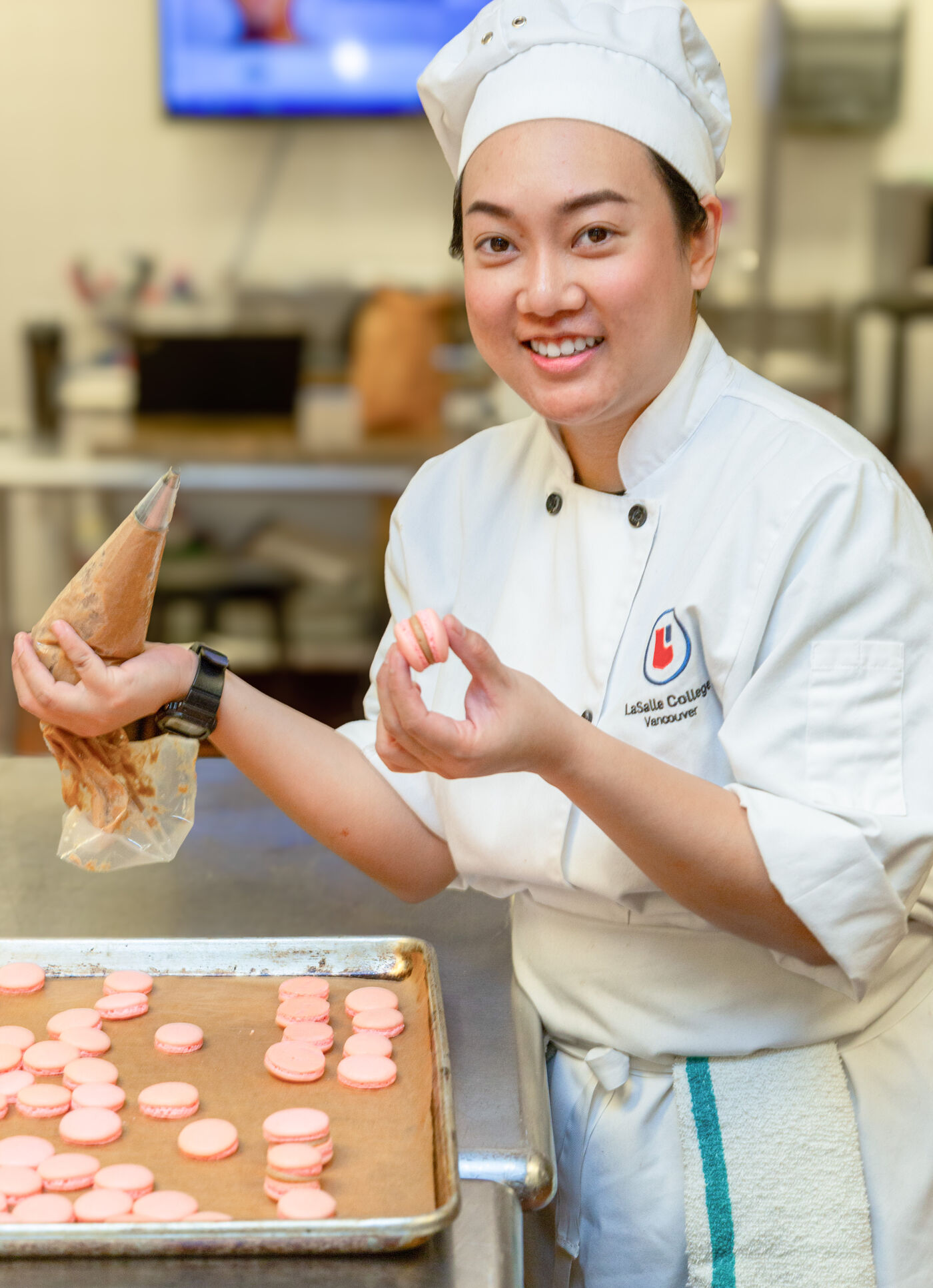 A chef joyfully prepares delicate macarons, showcasing culinary artistry.
