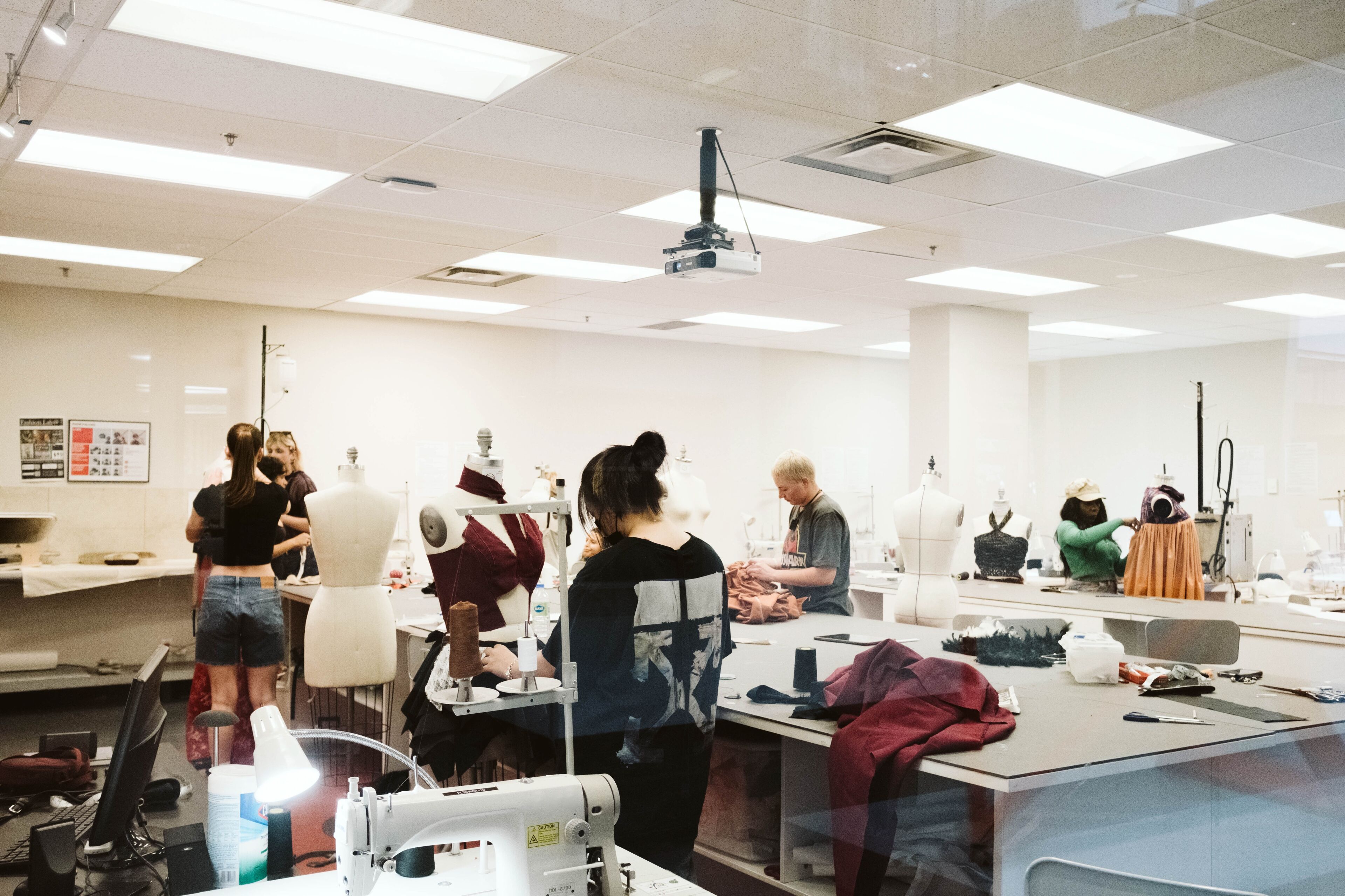 Students and instructors engaged in garment creation in a fashion design studio.