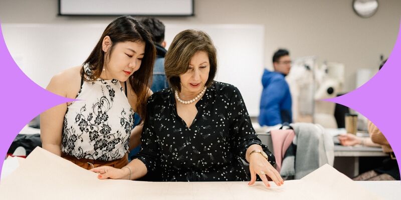 An experienced designer guides a young student through the nuances of fabric selection in a fashion design class.