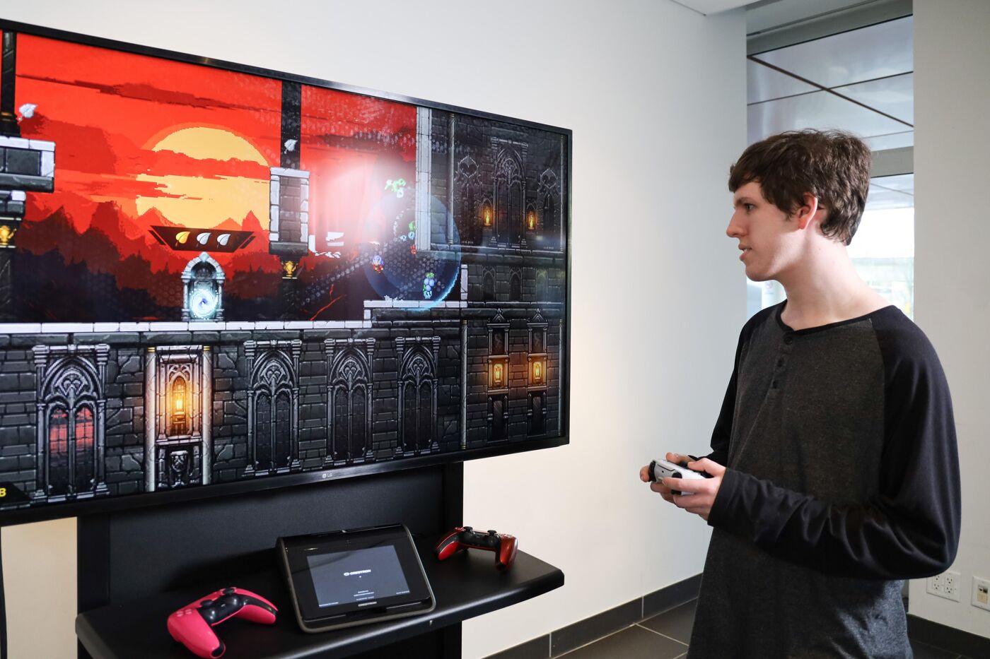 A young man plays a video game on a large screen, holding a controller in his hands.
