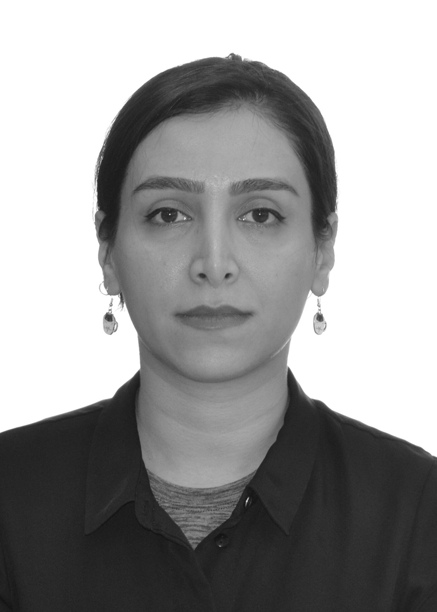 Close-up black and white shot of a woman with dark hair pulled back, wearing a collared shirt and earrings, against a white background.
