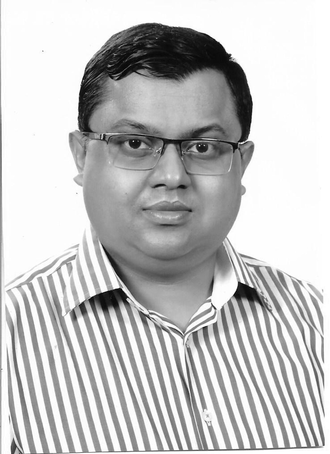 Close-up black and white shot of a man with glasses and a striped shirt.