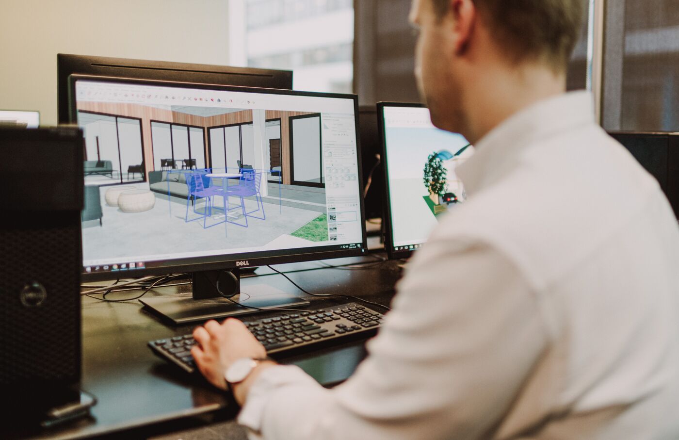 An architect meticulously refines a 3D model of a modern interior on his computer.