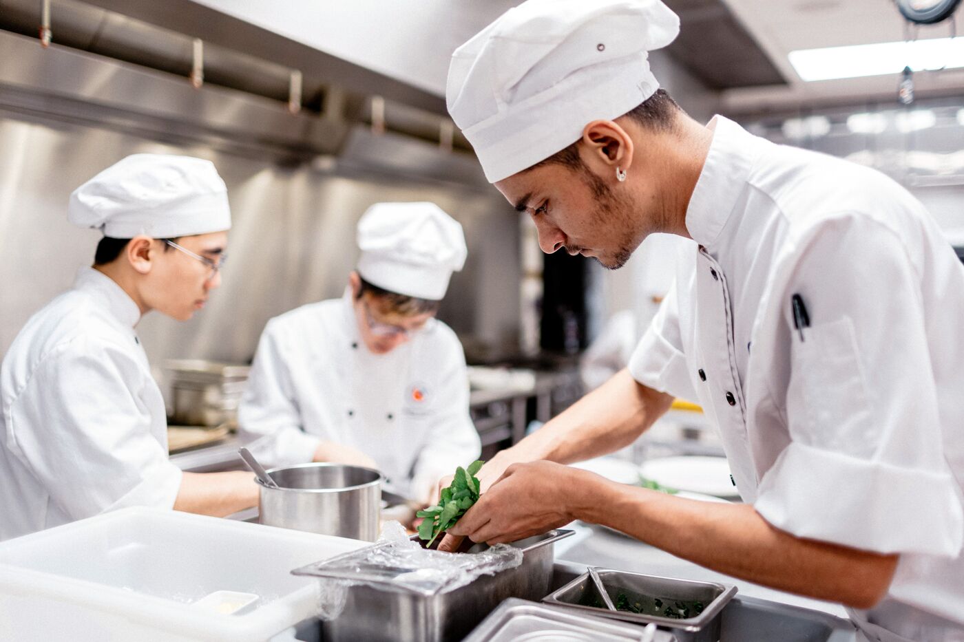 A chef attentively preps vegetables in a busy professional kitchen.