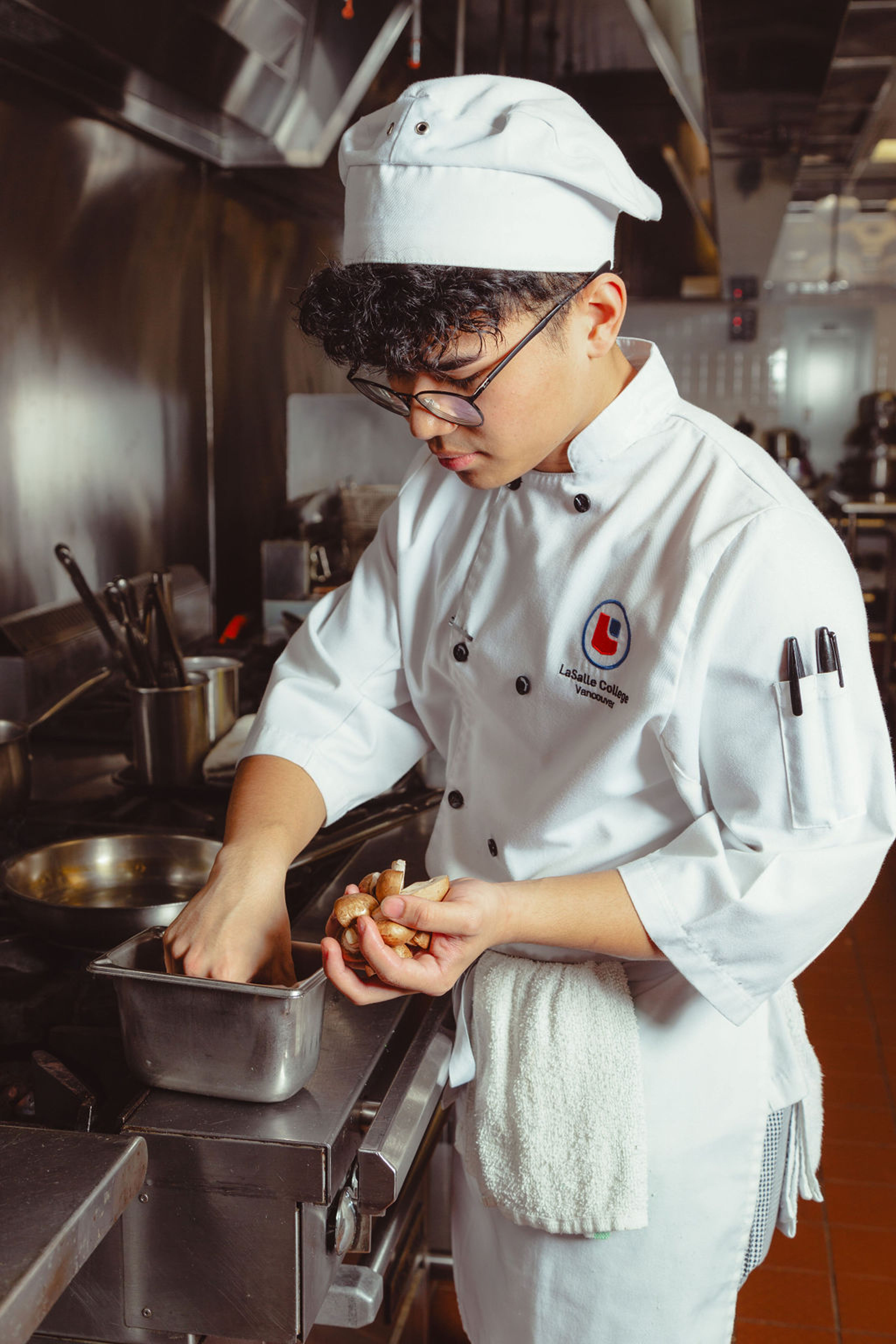 A focused chef at LaSalle College Vancouver inspects mushrooms before cooking.