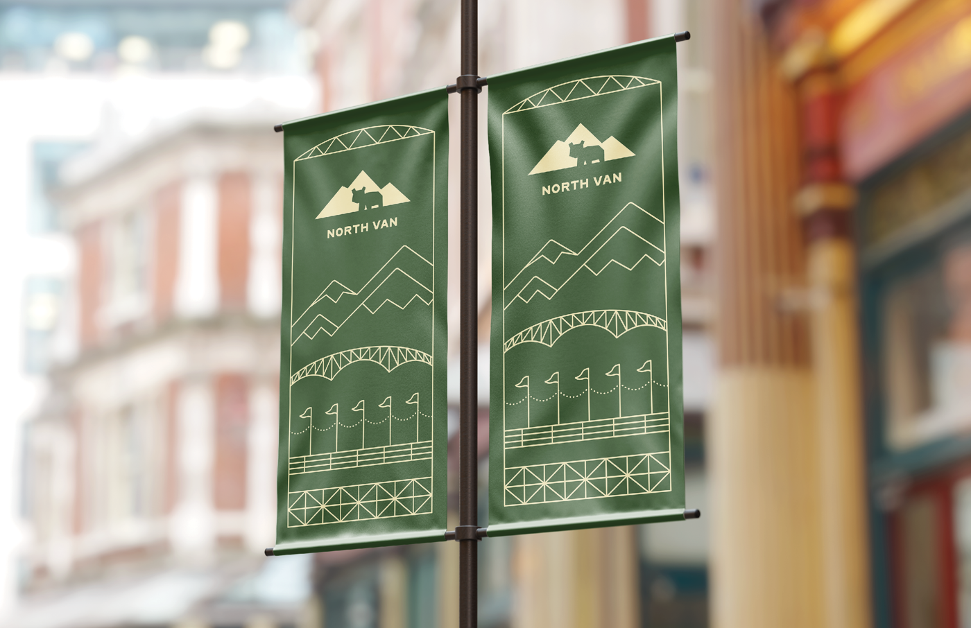 Green banners featuring a geometric design with mountains, bridges, and the text "NORTH VAN". They are displayed on a pole in an urban setting.