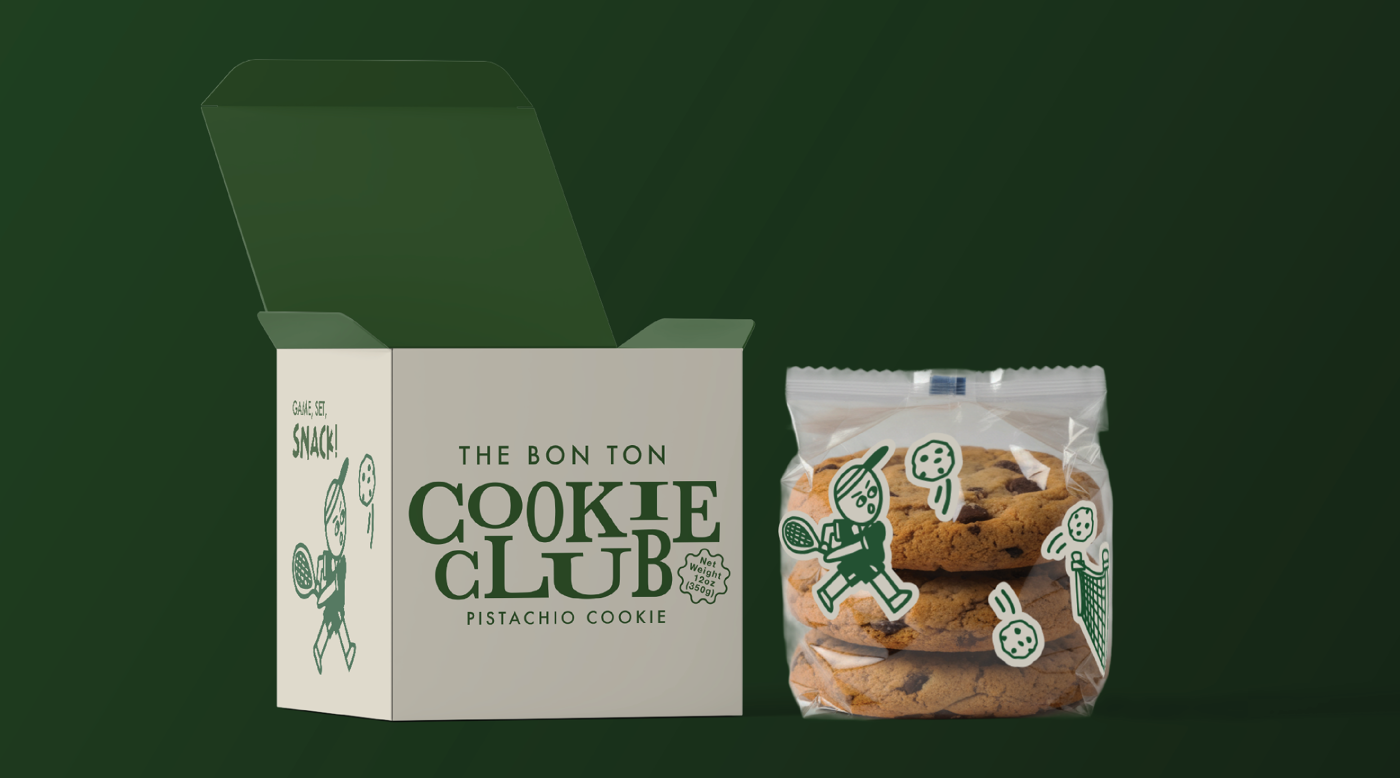 An open box of "The Bon Ton Cookie Club" with packaged pistachio cookies beside it, featuring a retro and playful design with characters playing tennis.