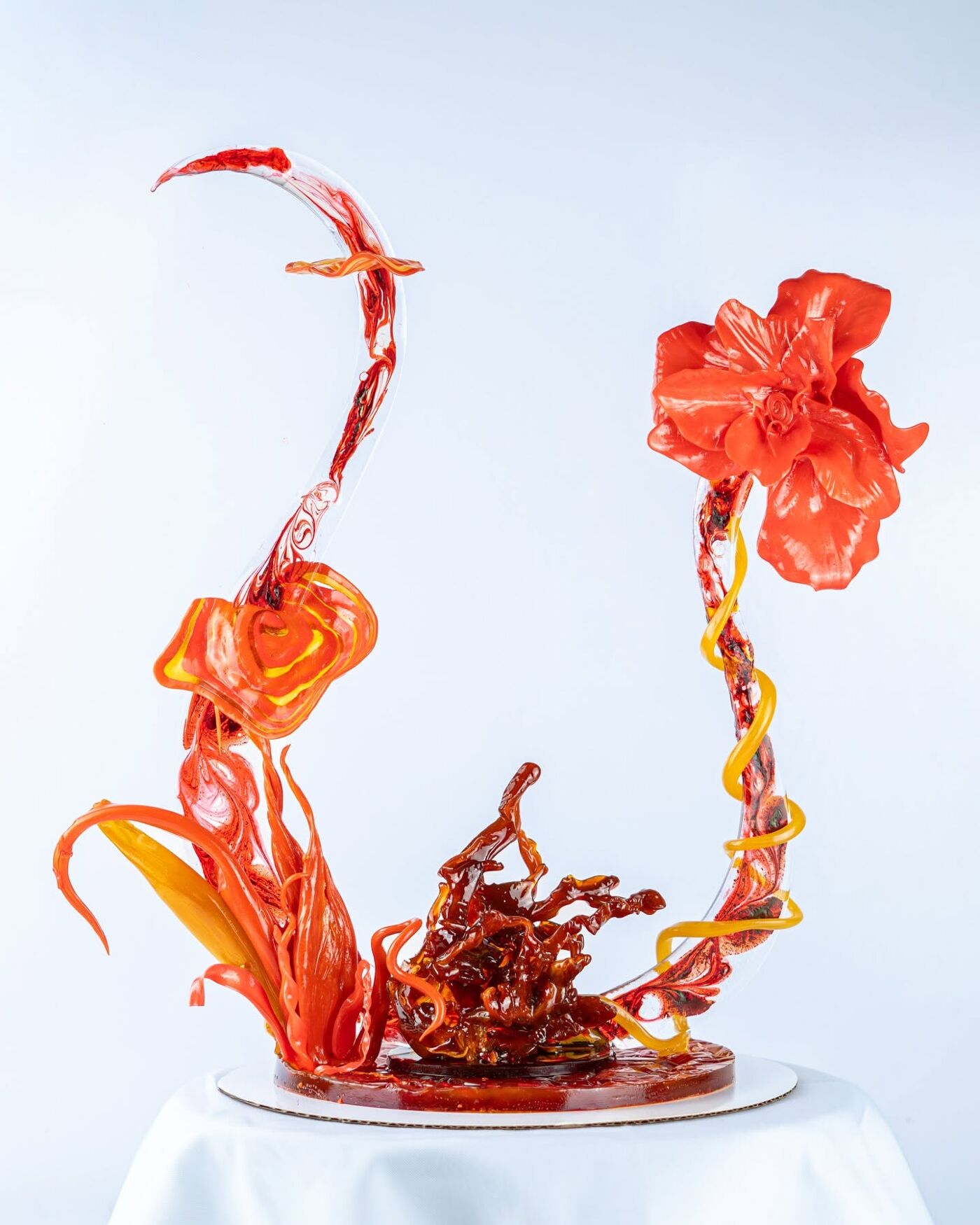 An impressive red and yellow sugar sculpture appears to evoke flames and a flower, with a dynamic and fluid design.